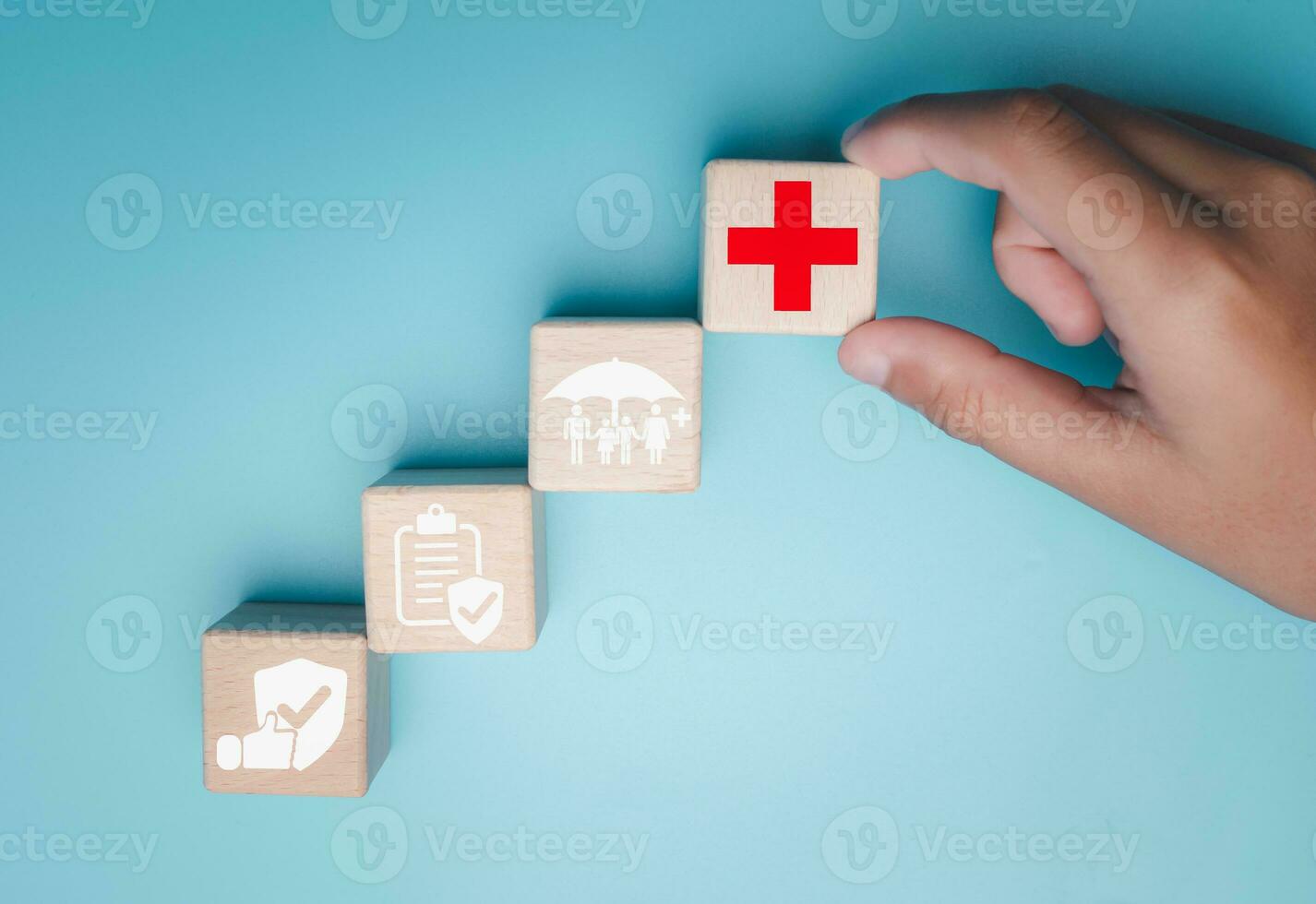 Health insurance and healthcare concept, human hand holds wooden block with icons about health insurance and healthcare access, retirement planning on blue background. photo