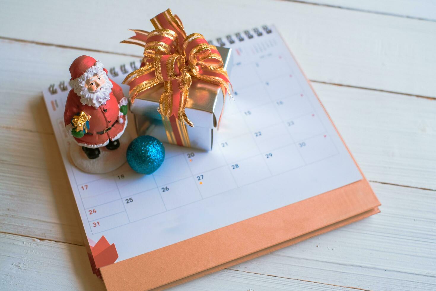 Red gift box on calendar isolated on white wooden background with. Christmas's day concept. Planning scheduling agenda, Event, organiser x'mas day. Flat lay, top view. photo