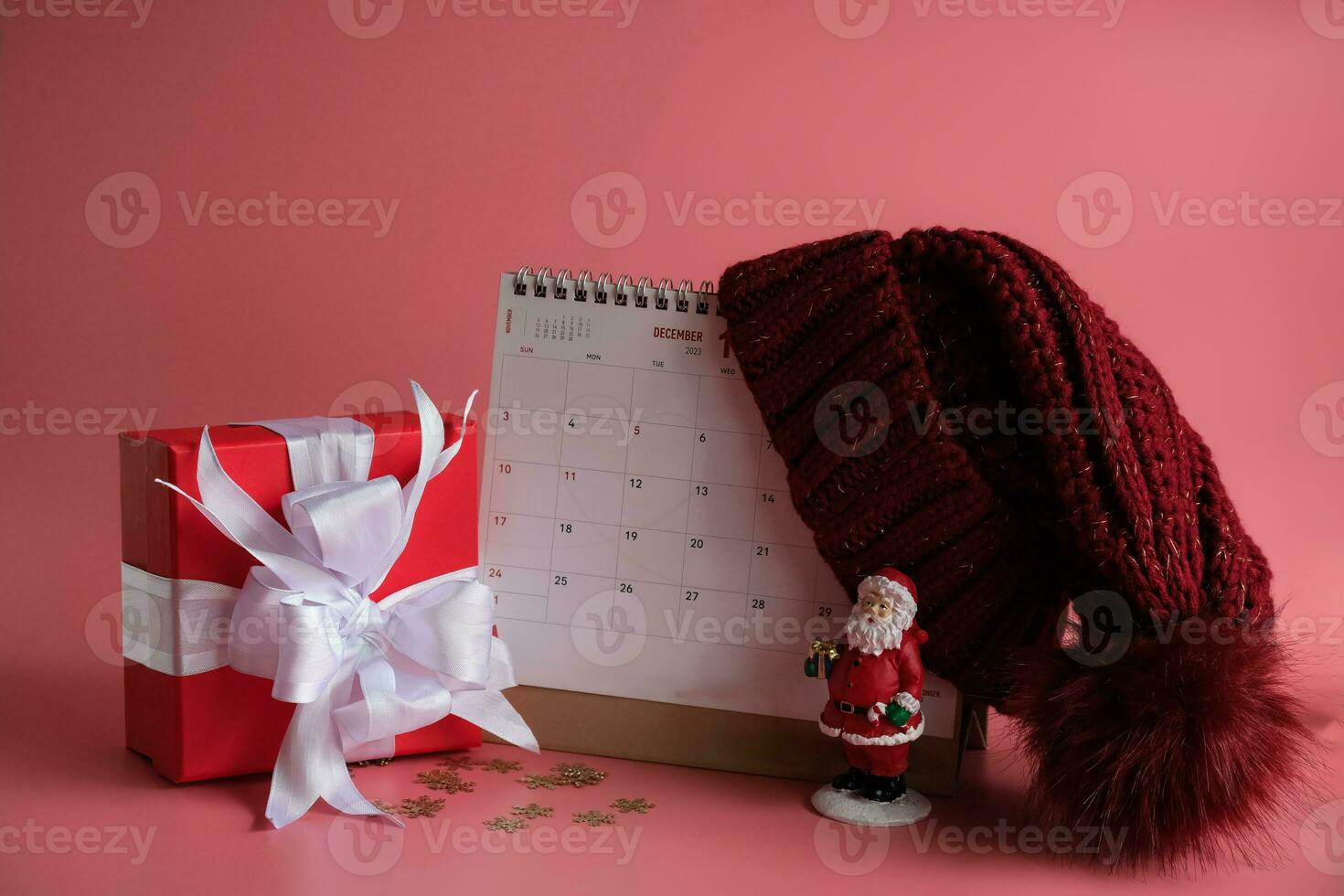 Gift box and calendar with a red knitted wool hat on pink background. Christmas's day concept. Planning scheduling agenda, Event, organiser x'mas day. photo