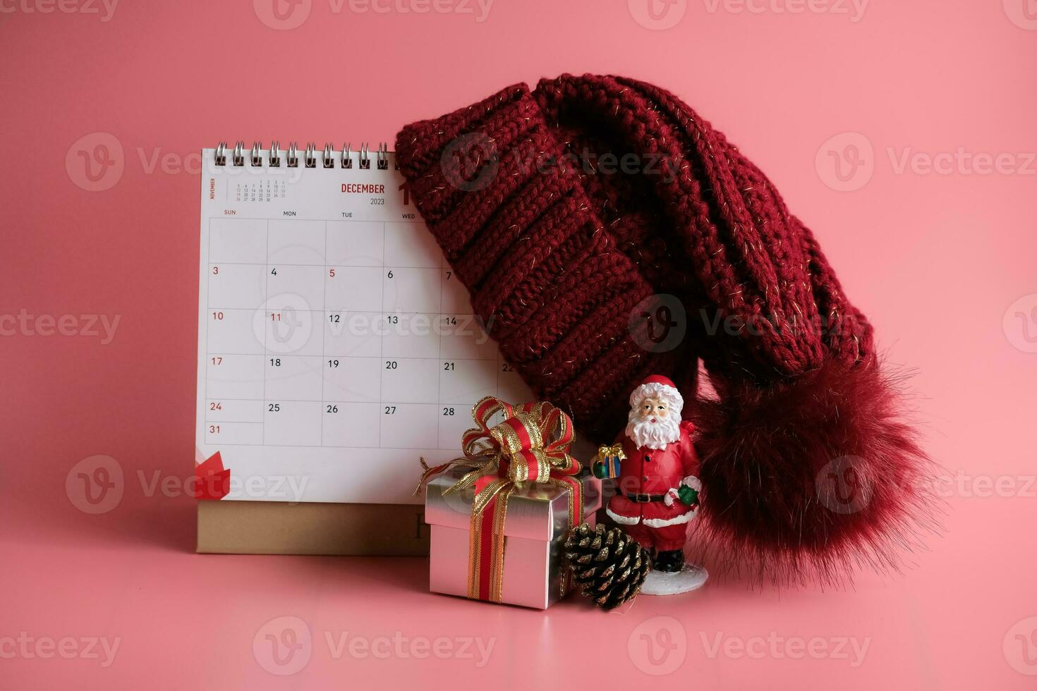 regalo caja y calendario con un rojo de punto lana sombrero en rosado antecedentes. navidad día concepto. planificación Planificación agenda, evento, organizador Navidad día. foto