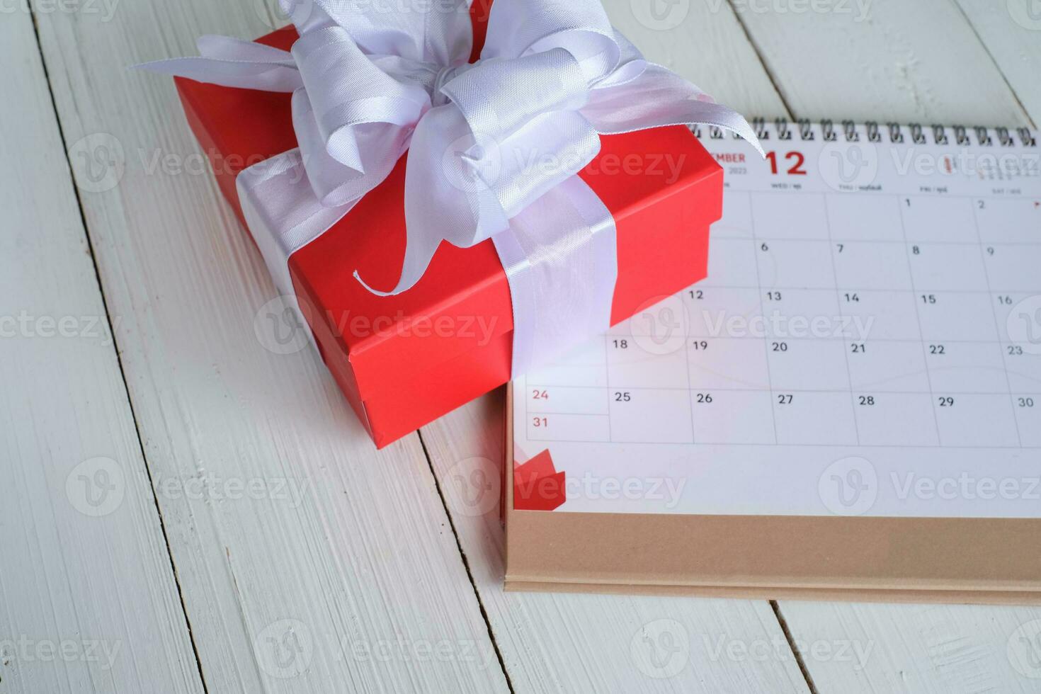 Red gift box on calendar isolated on white wooden background with. Christmas's day concept. Planning scheduling agenda, Event, organiser x'mas day. Flat lay, top view. photo