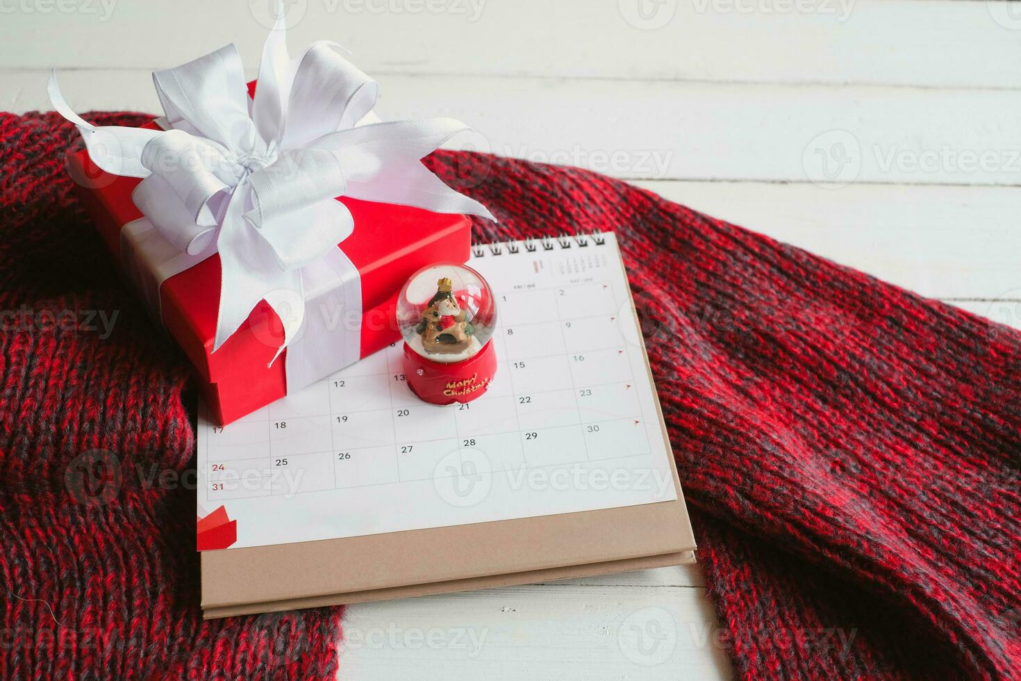 Gift boxes on knitted scarf a red scarf on white wooden table top view. Warm new year. Flat lay, top view. photo