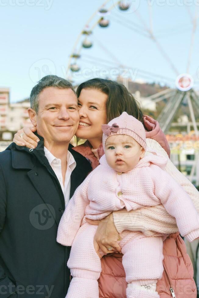 Outdoor portrait of happy family with adorable baby girl at Christmas market photo