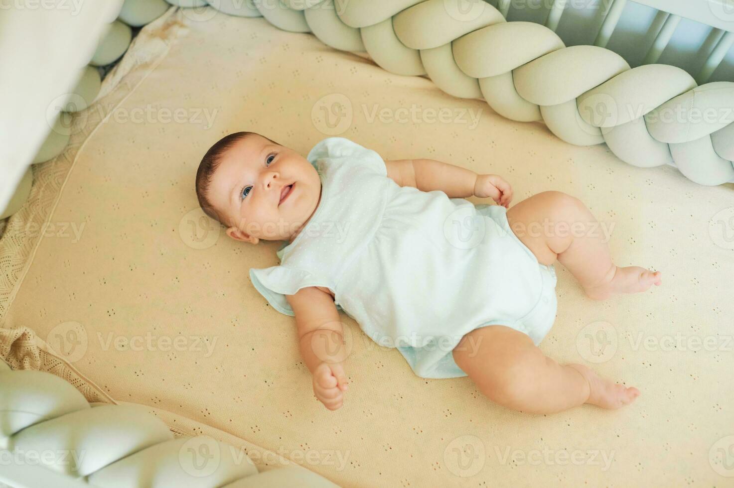 Adorable happy baby lying in crib top view photo