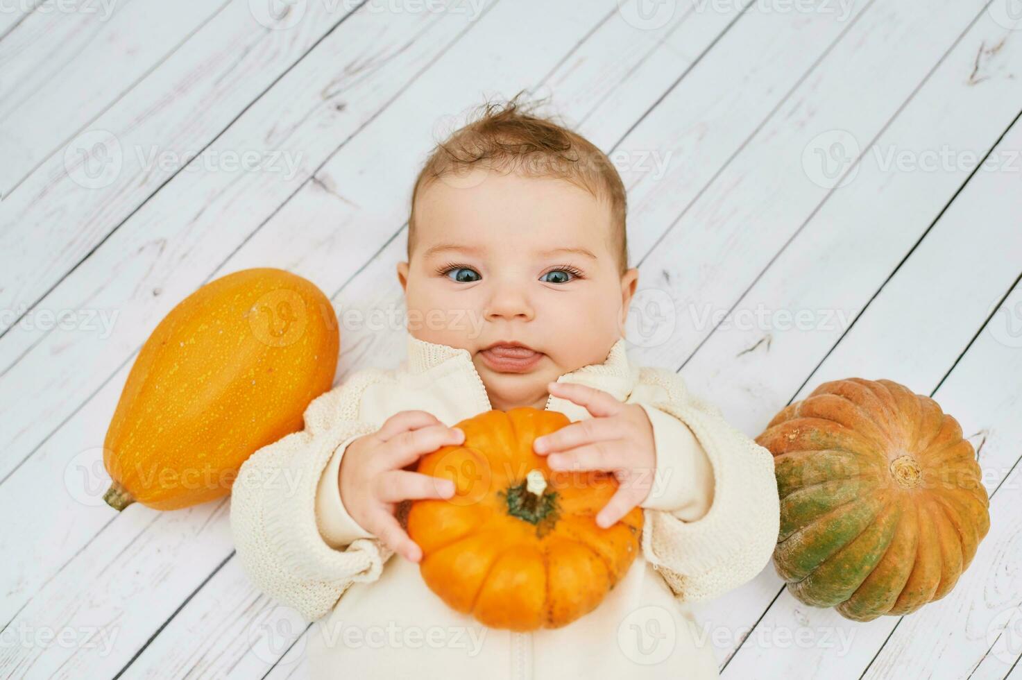 Autumn portrait of adorable baby playing with mini pumpkin photo