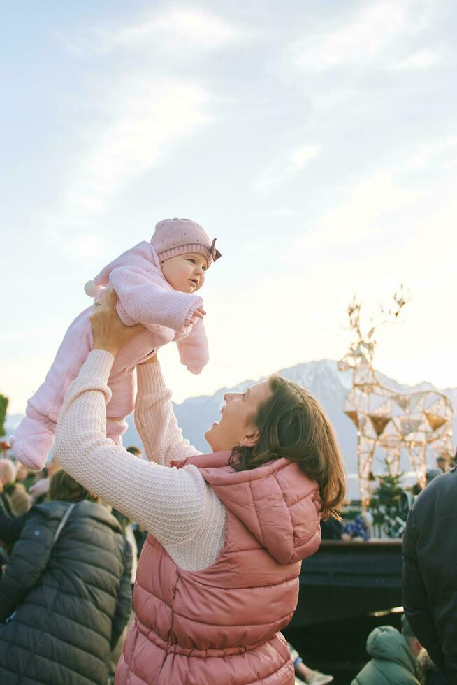 contento joven madre con adorable pequeño bebé visitando Navidad mercado foto