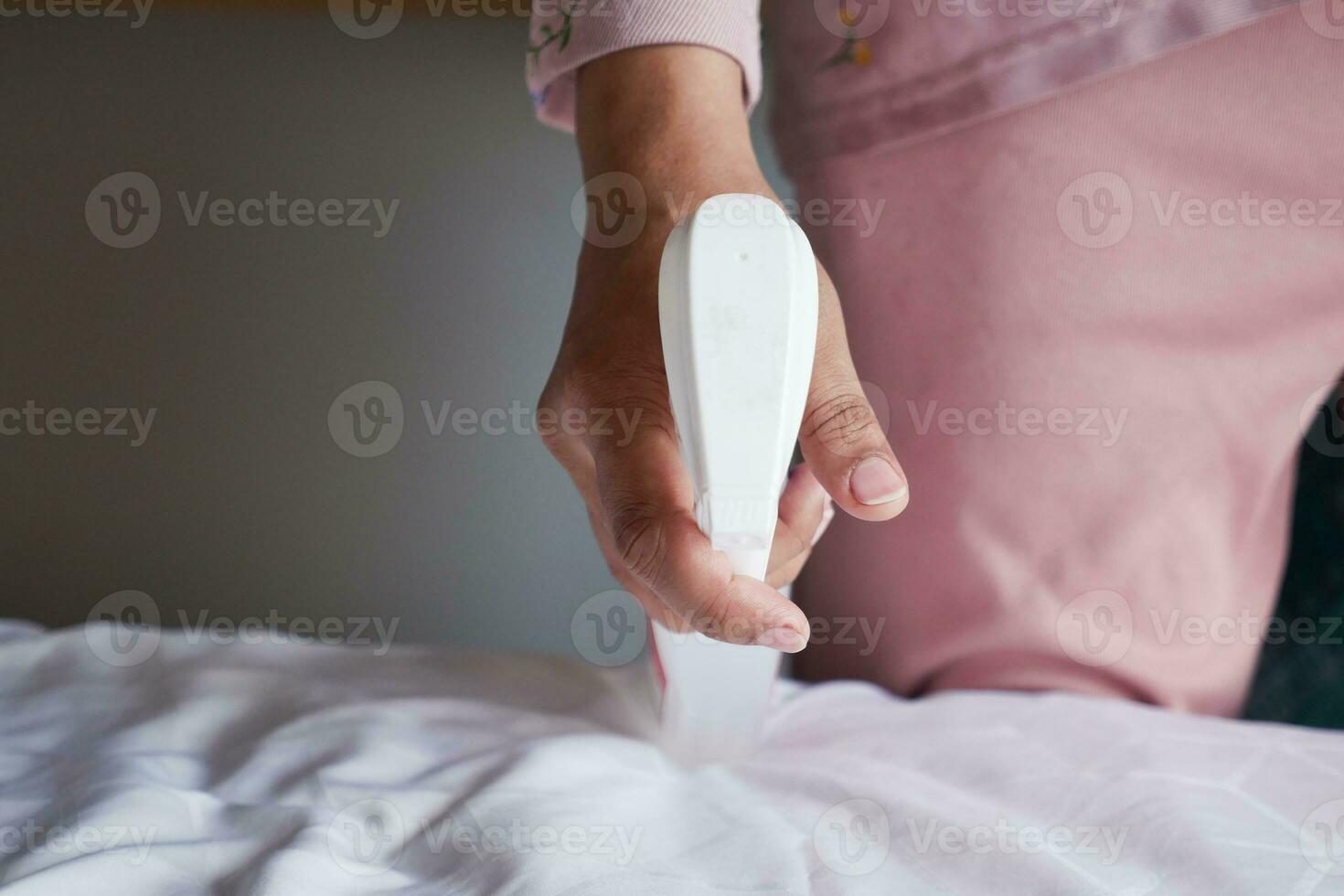 Woman use spray for clean the bed at home. photo