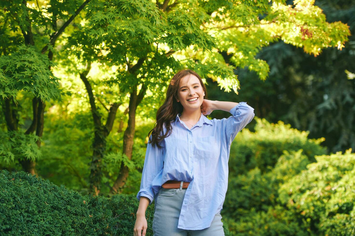 al aire libre retrato de contento joven mujer disfrutando ambiente en verde parque foto