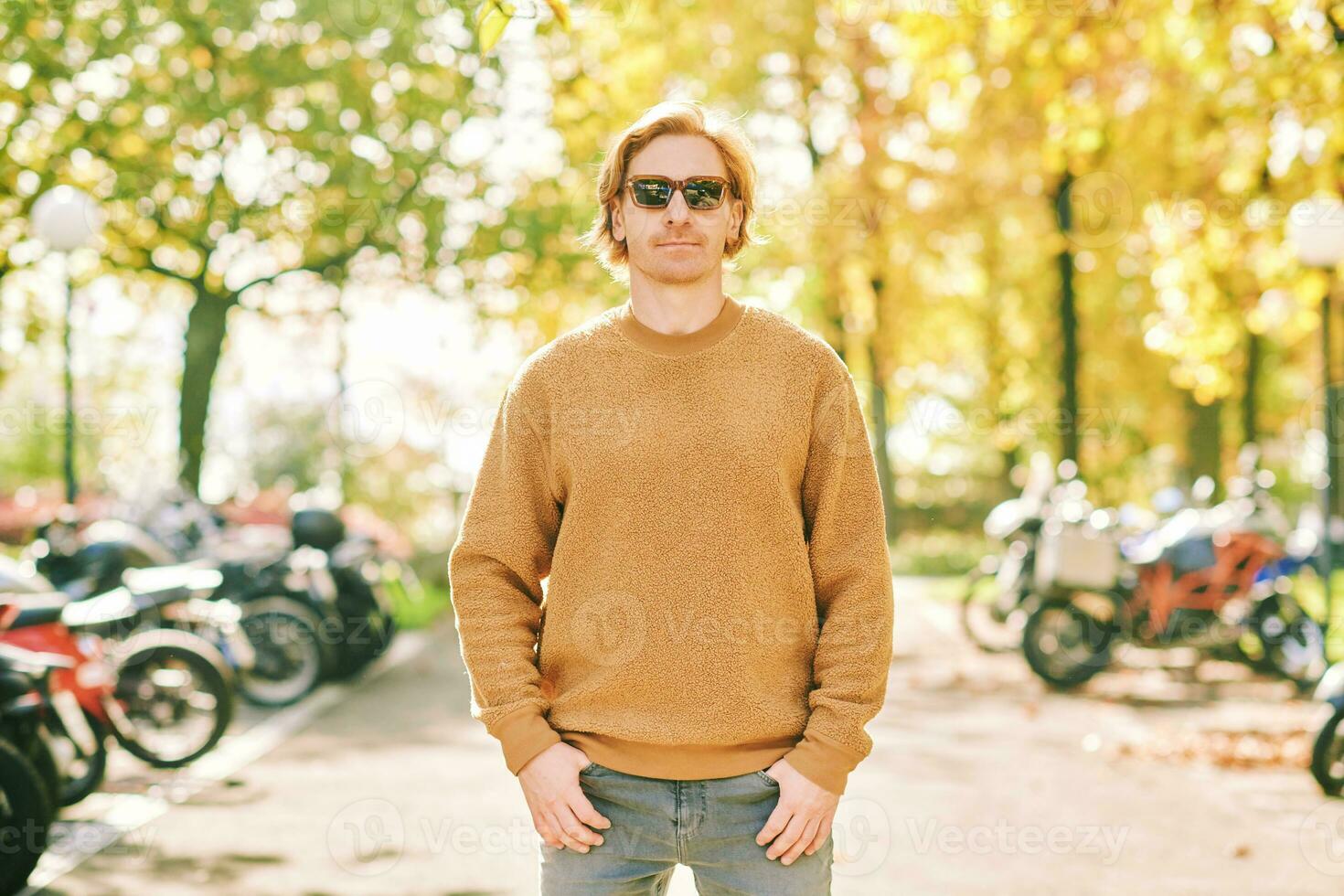 al aire libre otoño retrato de hermoso joven hombre vistiendo marrón borroso lana suéter y Gafas de sol foto