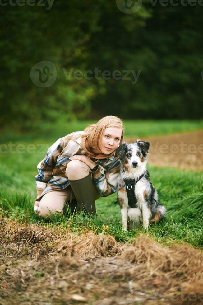 Outdoor portrait of beautiful young woman playing with australian shepherd dog photo