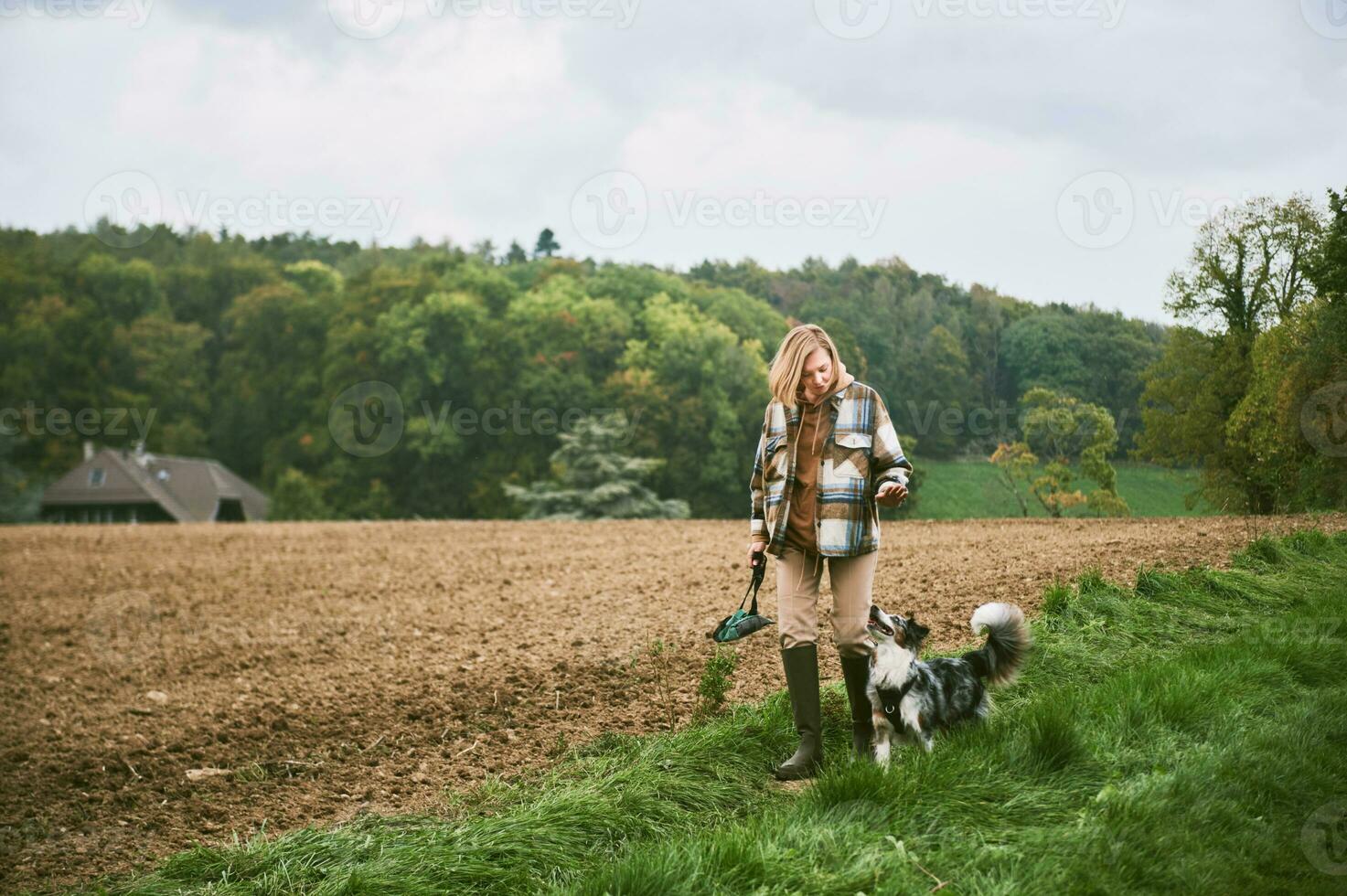 Farm landscape, young woman walking with australian shepherd dog photo