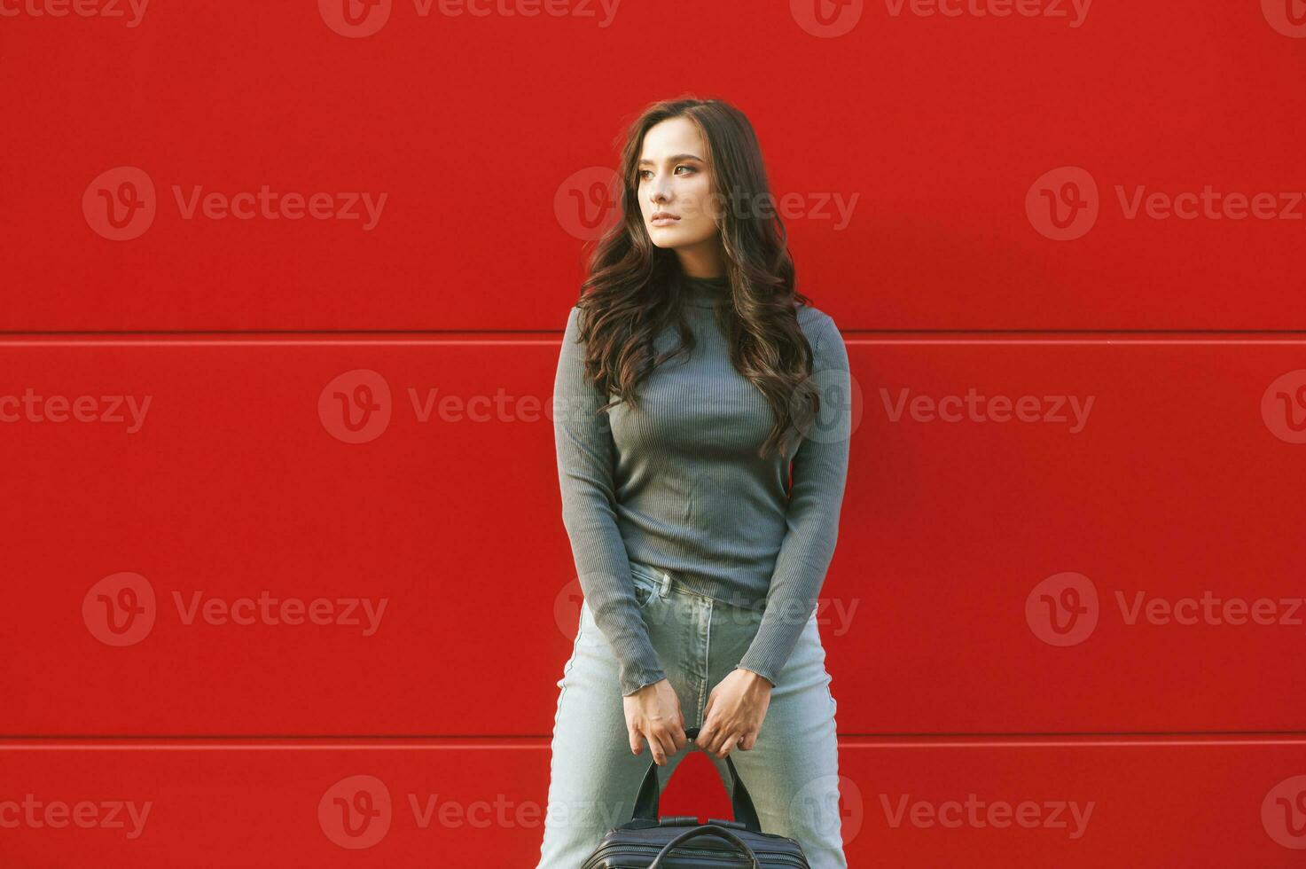 al aire libre retrato de joven bonito mujer posando en rojo fondo, vistiendo caqui capucha foto