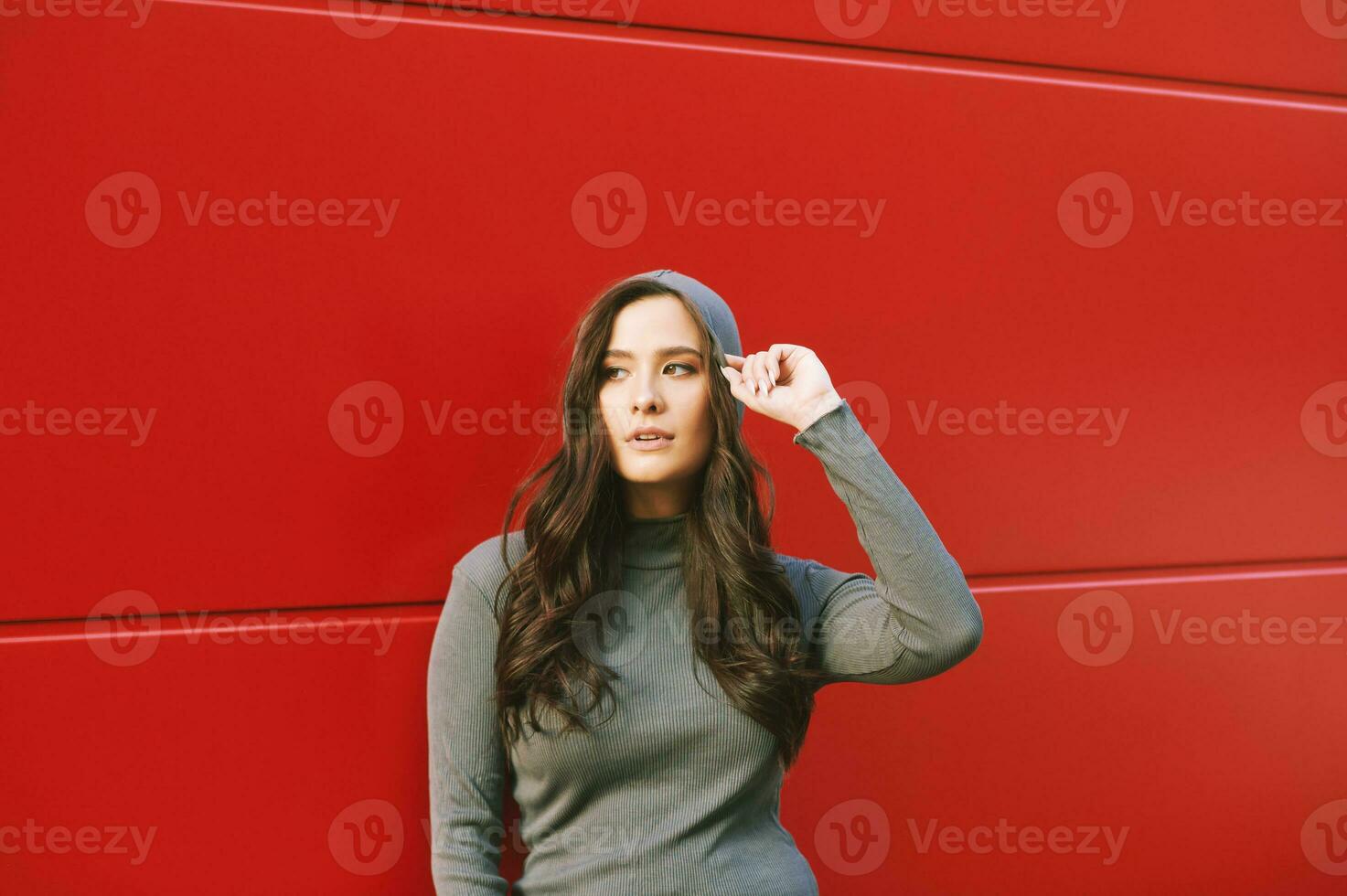 Outdoor portrait of young pretty woman posing on red background, wearing khaki hoodie photo