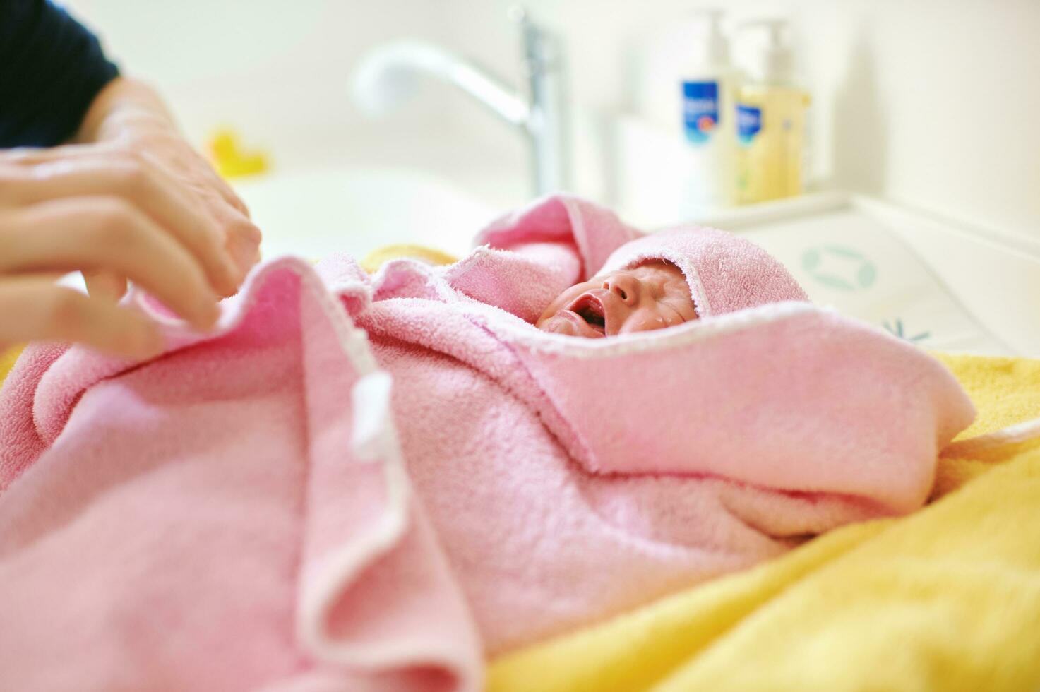 Newborn baby covered in towel after taking bath photo