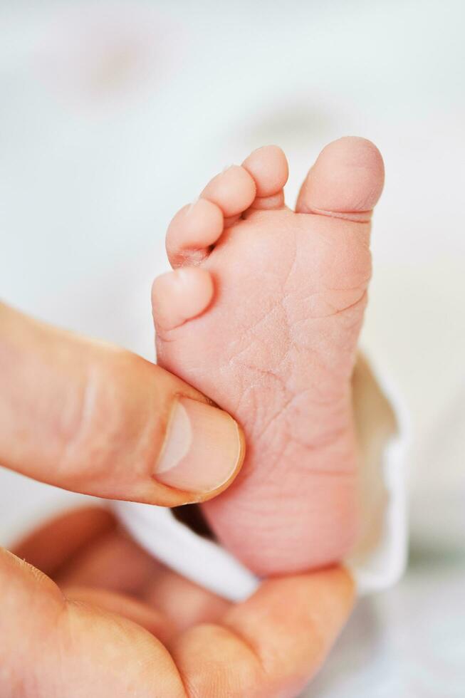 Close up image of tiny newborn baby feet holding by father photo