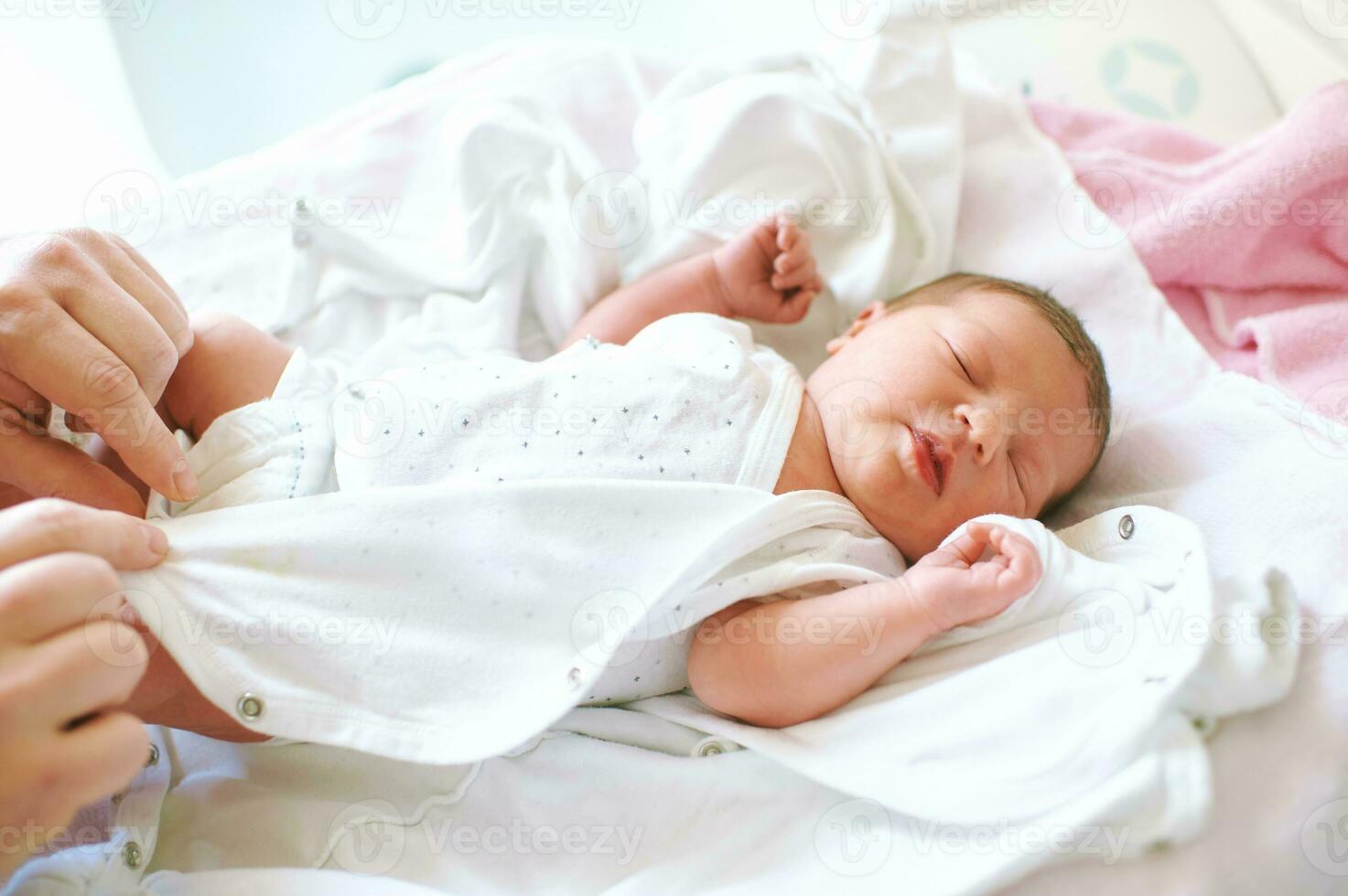 Parent changing newborn baby clothes, first hours of life photo