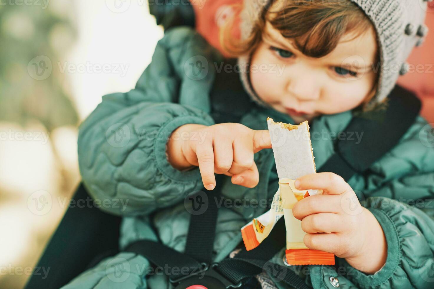 Happy toddler kid eating fruit bar, healthy snack, sitting in stroller photo