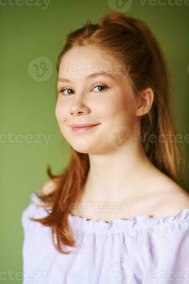 belleza retrato de bonito joven 15 - dieciséis año antiguo Pelirrojo adolescente niña vistiendo púrpura vestir posando en verde antecedentes foto