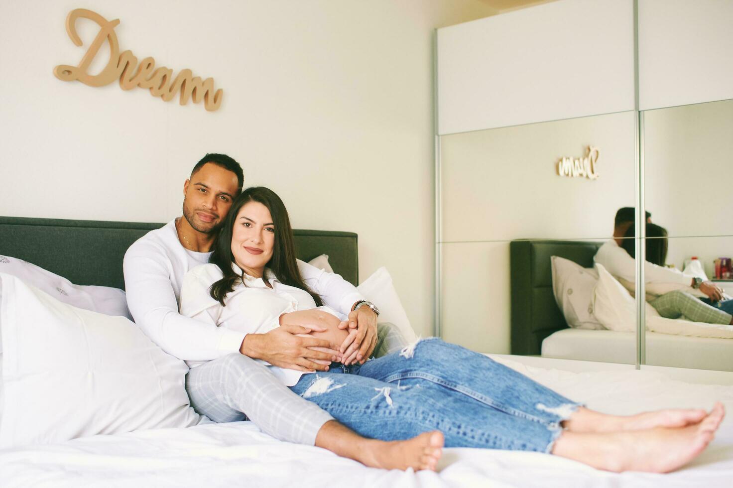 interior retrato de contento joven familia, embarazada mujer con su amoroso marido relajante en cama foto