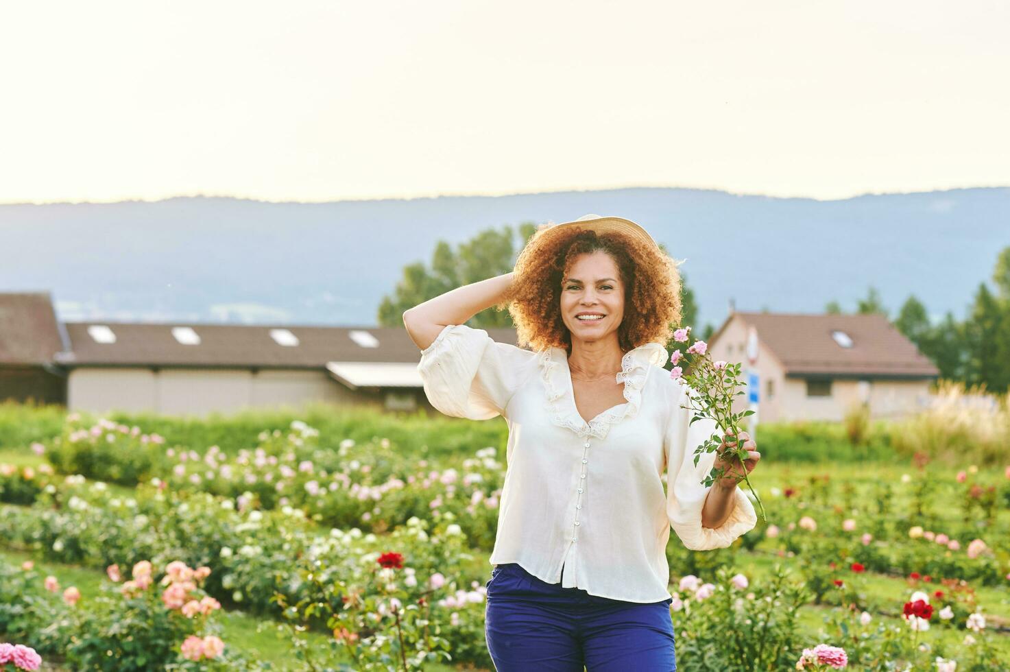 Countryside lifestyle, outdoor portrait of beautiful middle age 50 - 55 year old woman enjoying nice day in flower farm garden photo