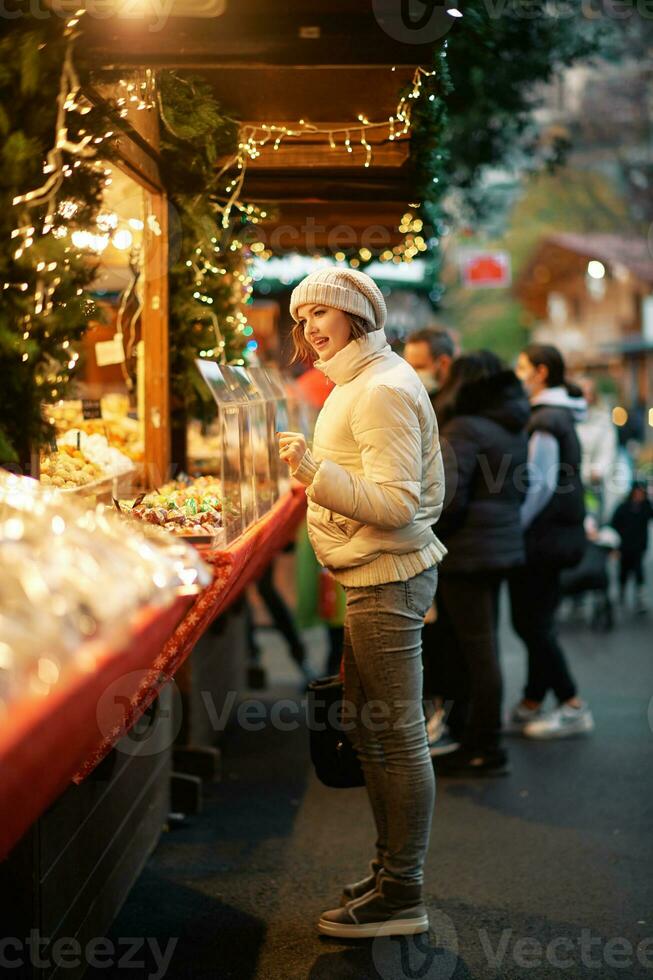 Outdoor portrait of young woman buying sweets at Christmas market photo