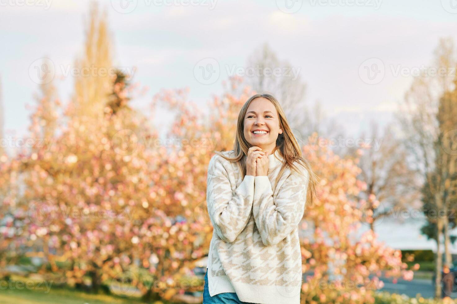 Outdoor portrait of young happy blond woman in spring park, emotional female model having fun on sunny warm day photo