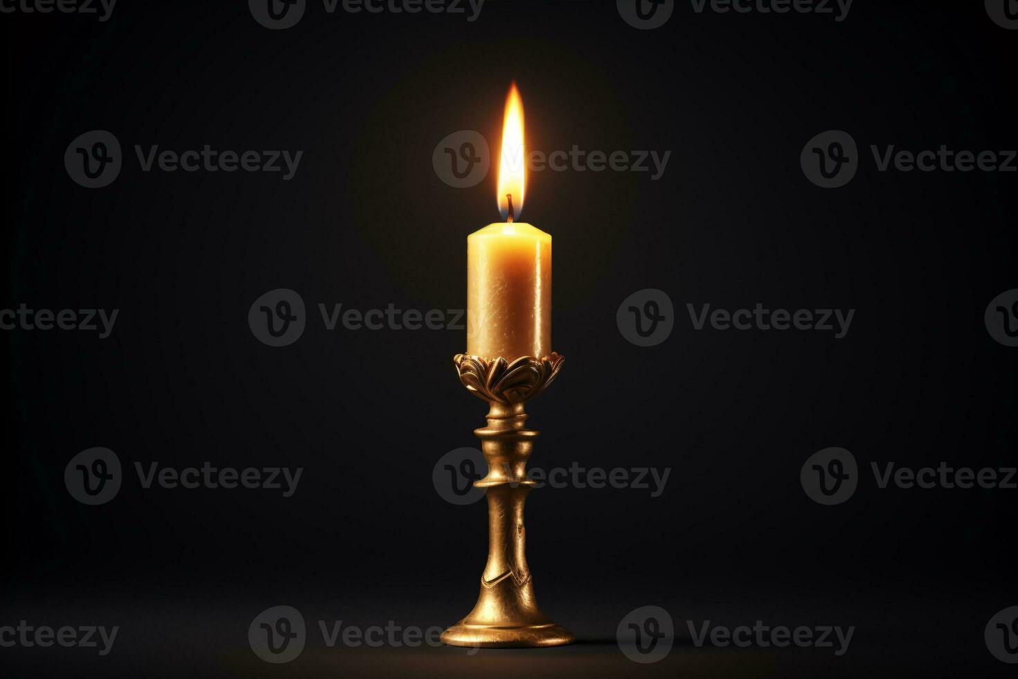 A vintage candle burning in an antique golden candlestick is set against a black backdrop. photo