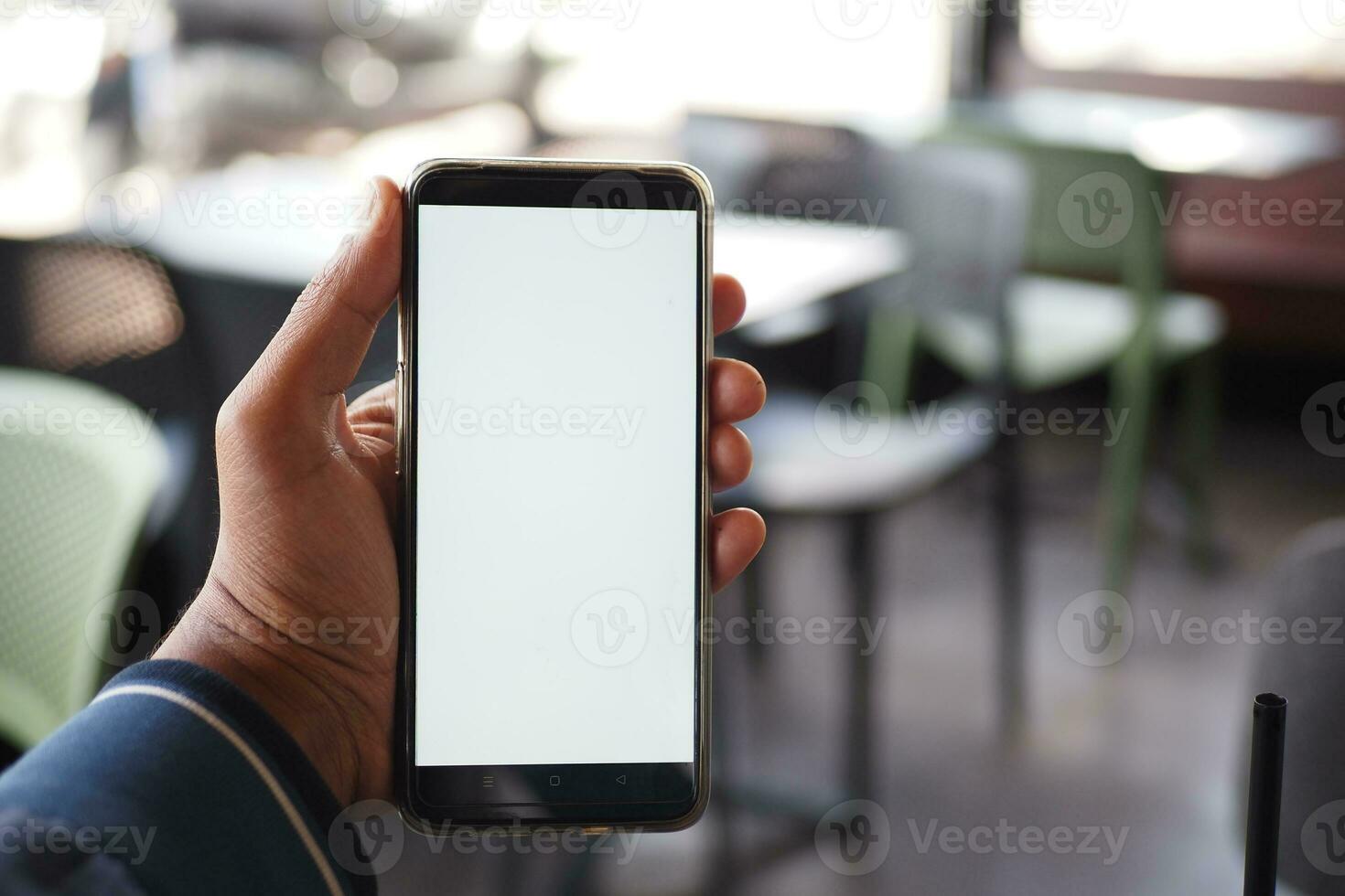 young man hand using smart phone with white screen at cafe background photo