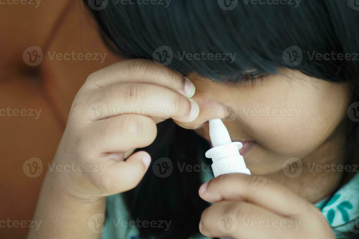 close up of sick child using nasal medicine spray photo