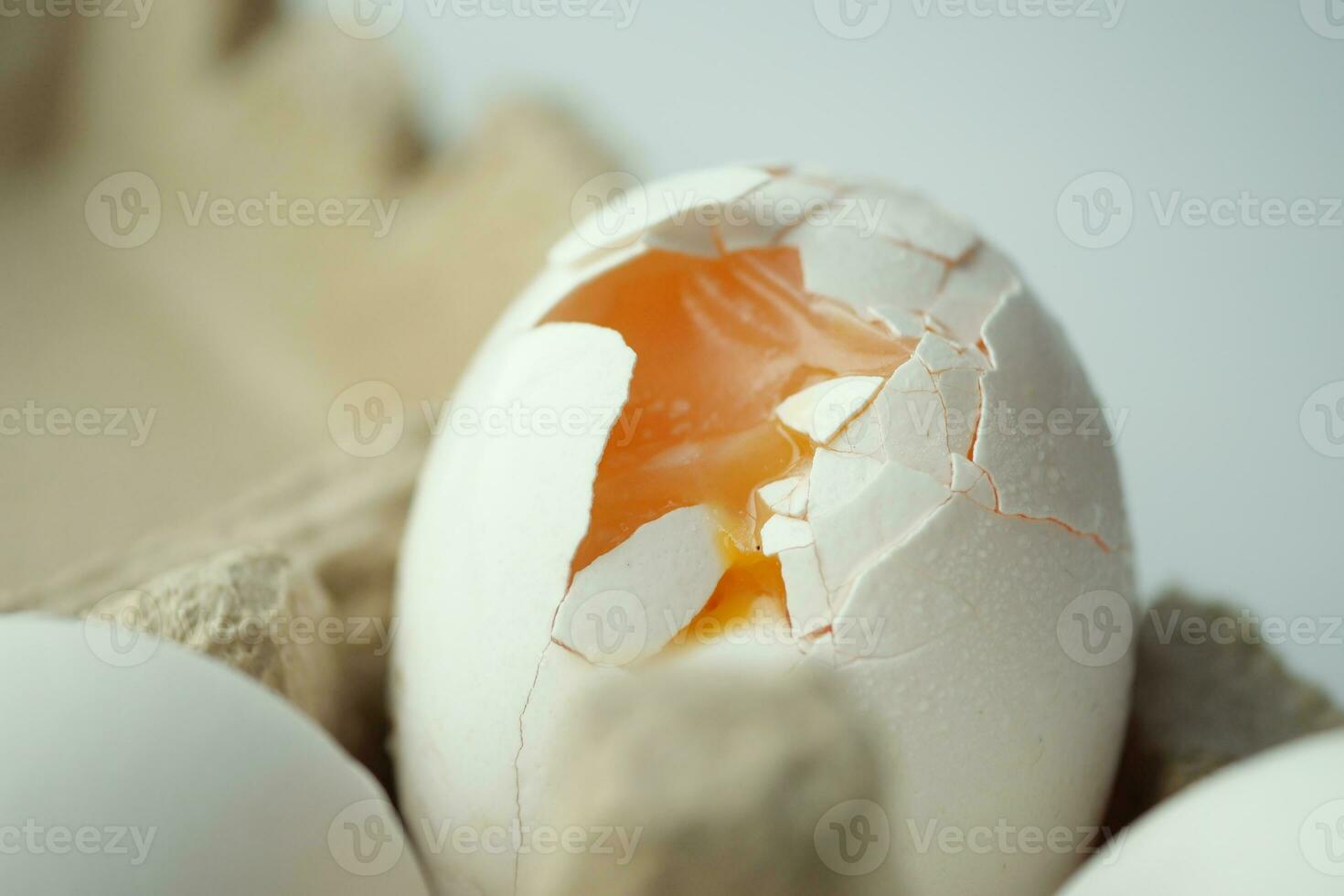 one broken egg with yellow yolk stored in carton container photo