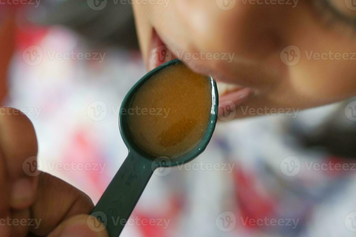 A child taking a dose of cough syrup. photo