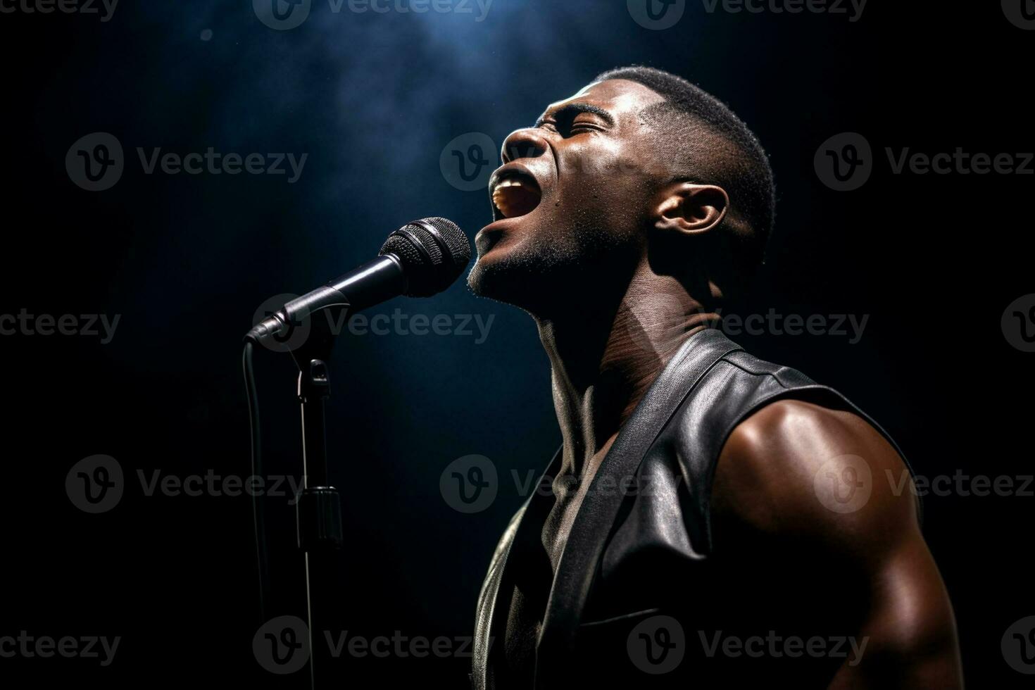 black male singer singing with microphone in front of dark background bokeh style background photo