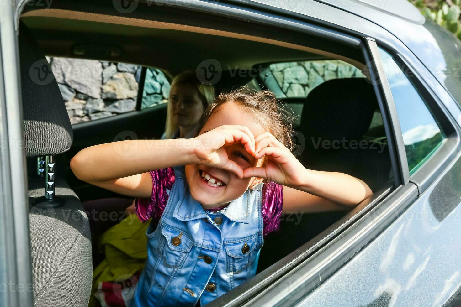 Little fun girl speeds in car near the open window photo