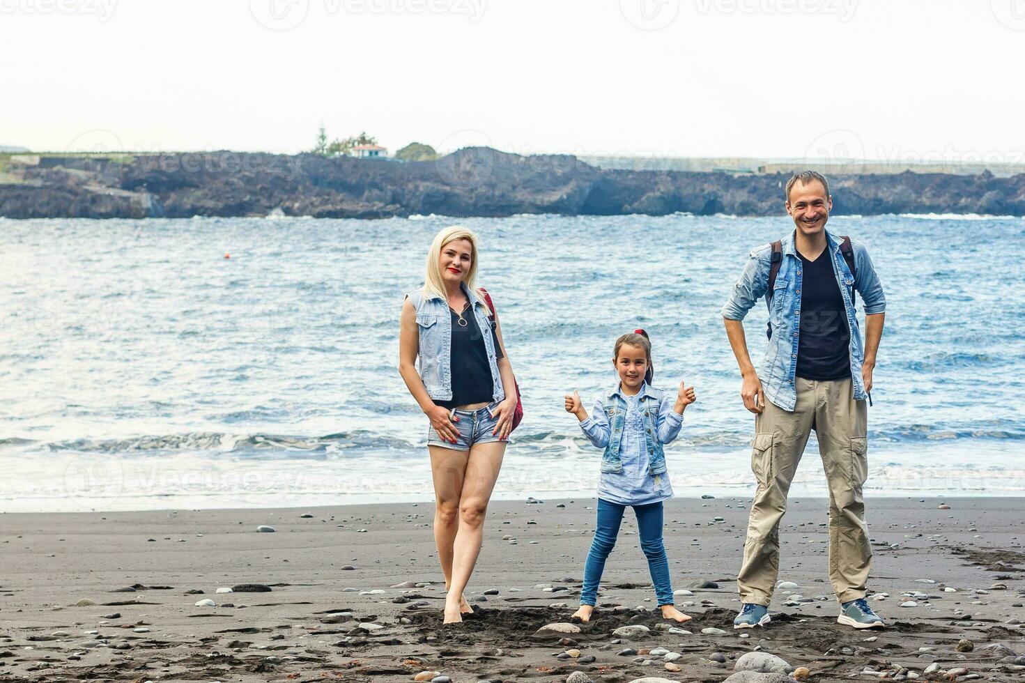 contento familia en pie en el playa en el amanecer hora foto