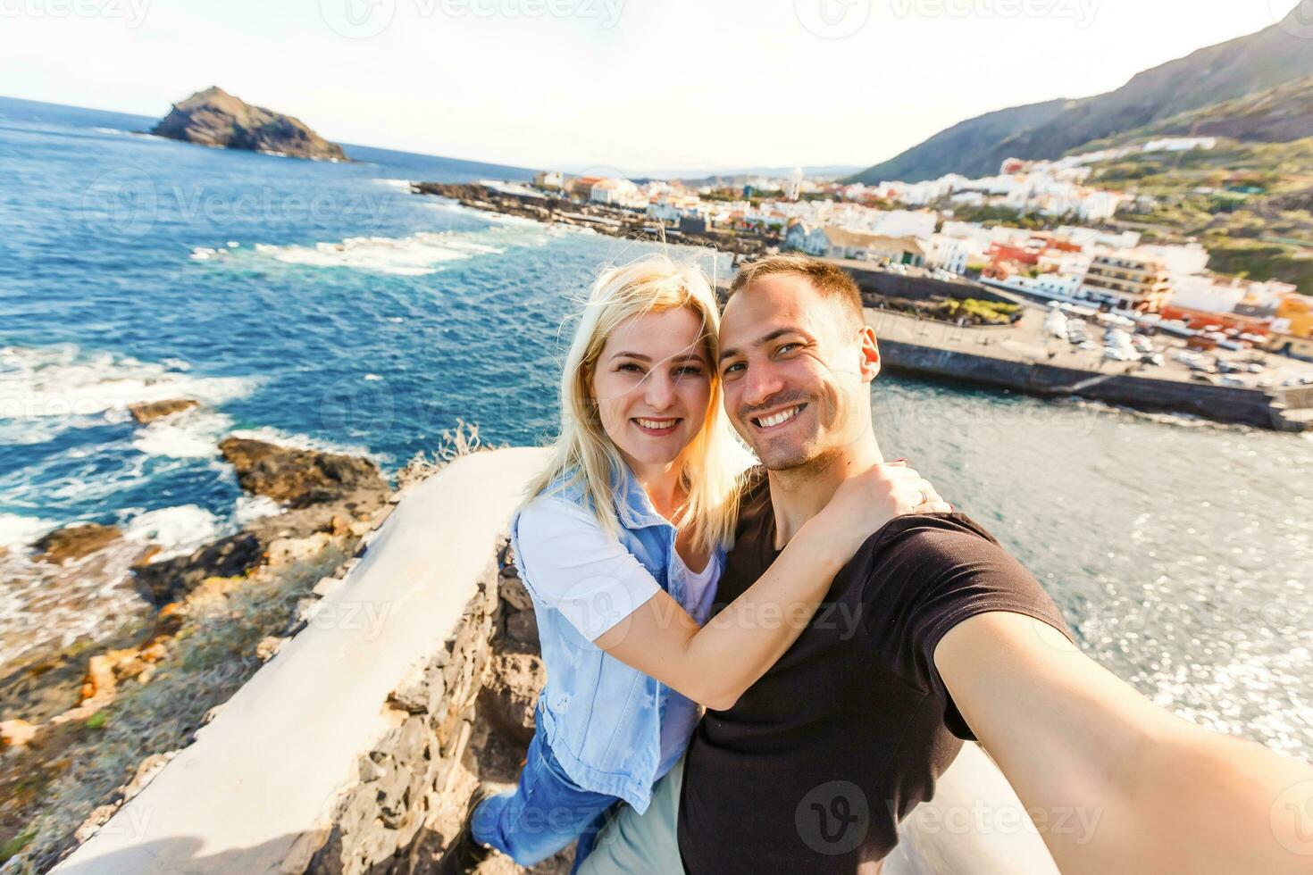 Young girl smiling and speaking consulting and giving instruction with voice recognition. Woman with audio recording in smart phone in the seaside in Garachico, Tenerife photo