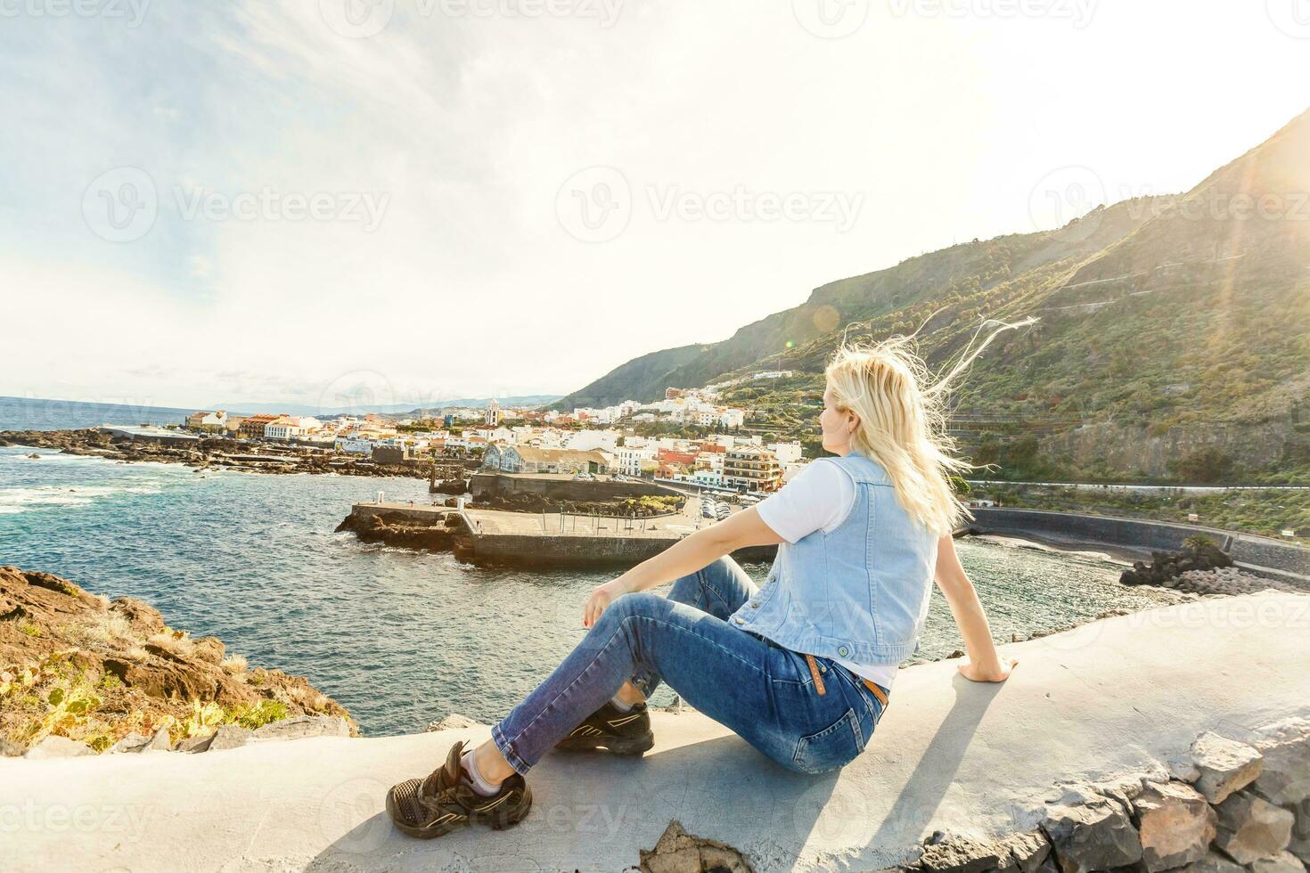 Young girl smiling and speaking consulting and giving instruction with voice recognition. Woman with audio recording in smart phone in the seaside in Garachico, Tenerife photo