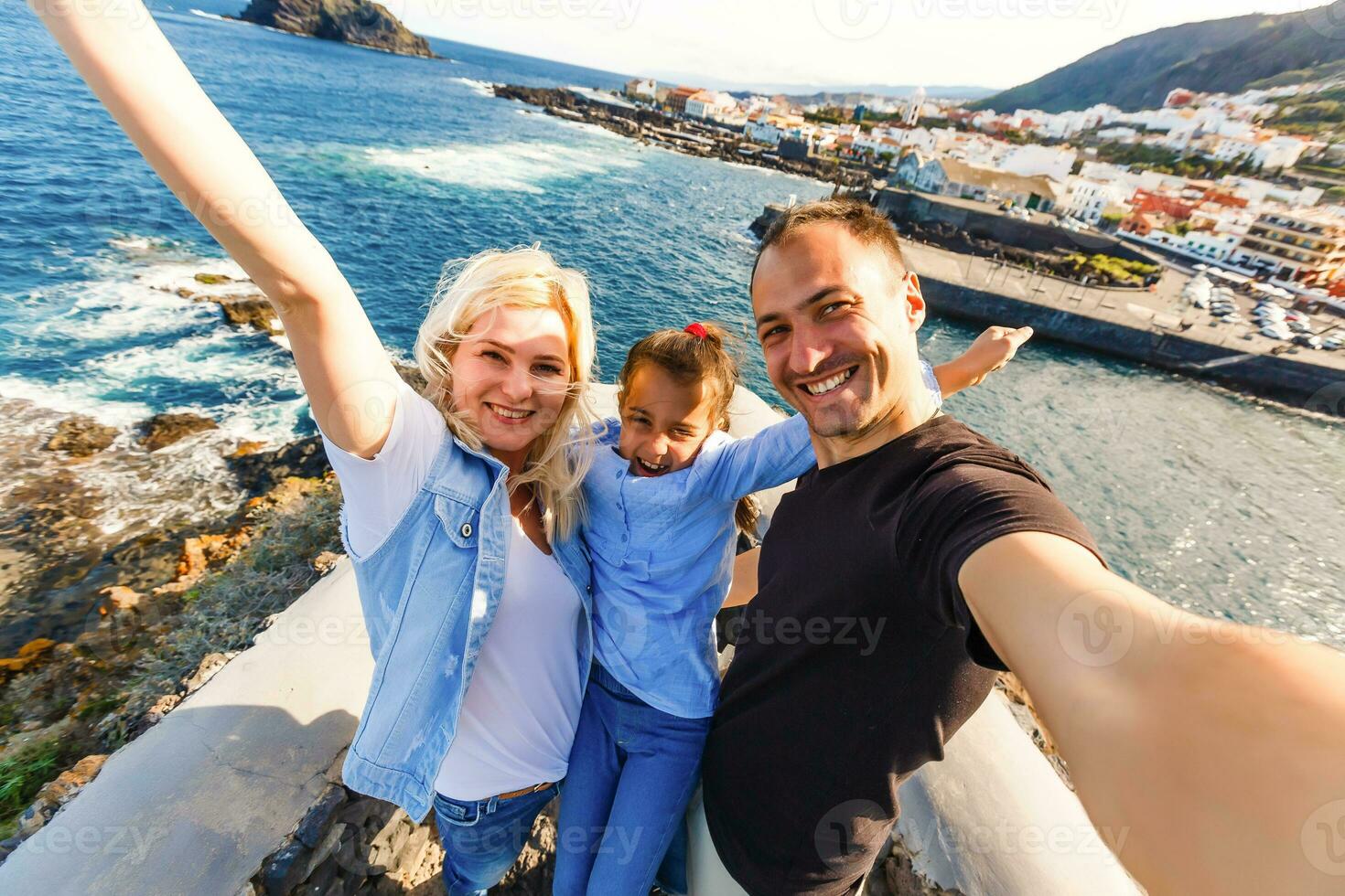 Young girl smiling and speaking consulting and giving instruction with voice recognition. Woman with audio recording in smart phone in the seaside in Garachico, Tenerife photo
