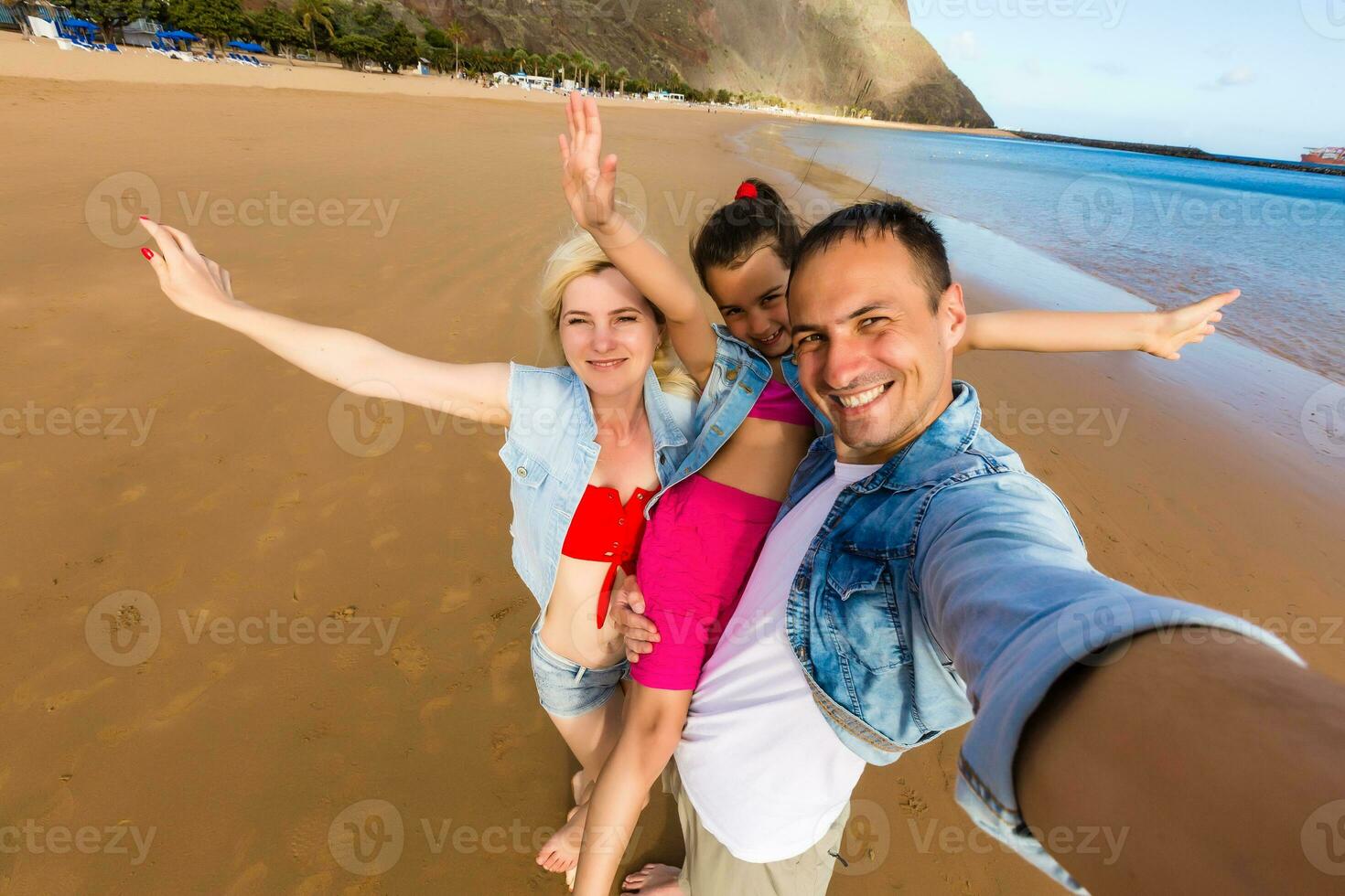 un joven Pareja y su hija son tomando un selfie a el playa foto