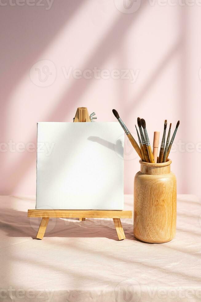 Blank white canvas and vase with paintbrushes for art. Artistic layout. photo