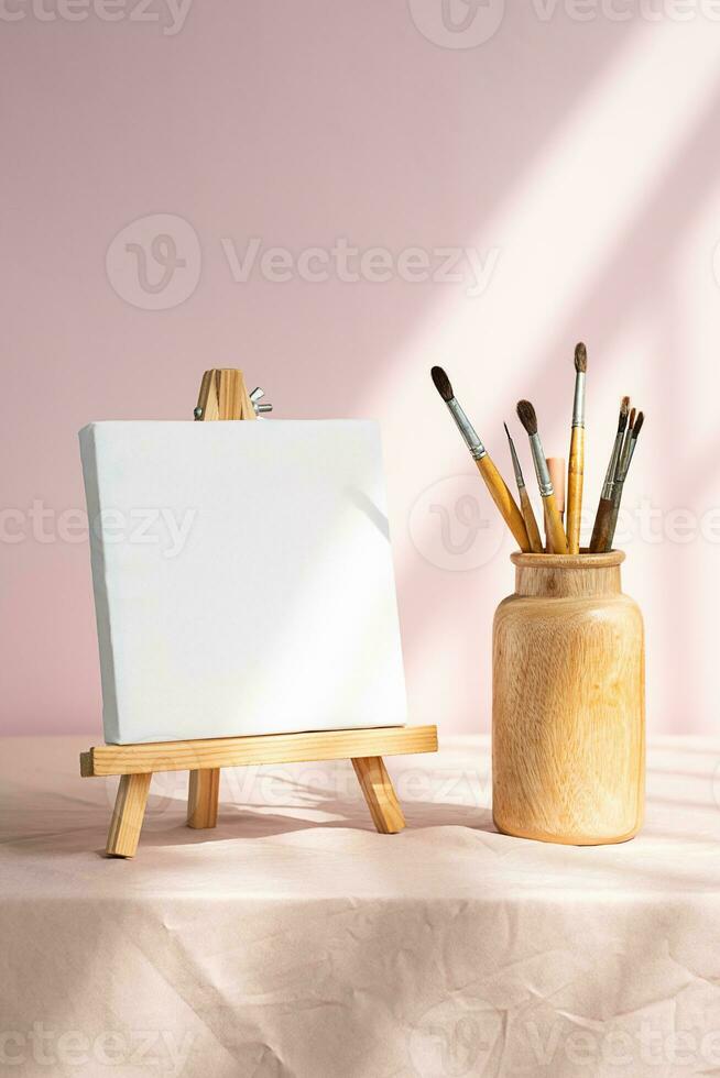 Blank white canvas and vase with paintbrushes for art. Artistic layout. photo