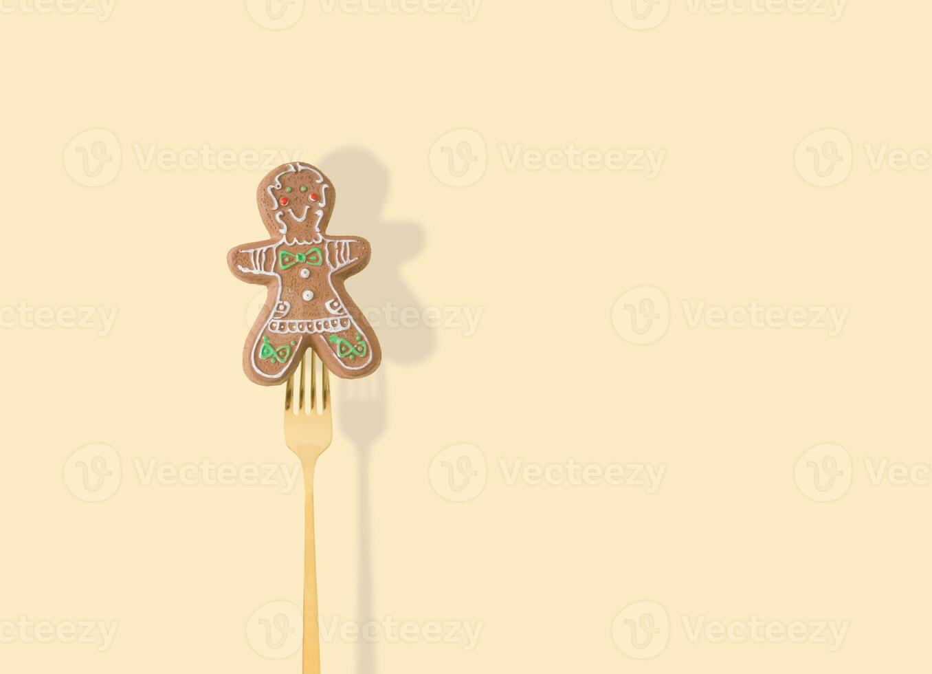 Gingerbread Christmas tree decoration pricked on a fork on pastel beige background. New Year party background. Minimal style. Creative Christmas or New Year concept. Winter holidays idea. photo