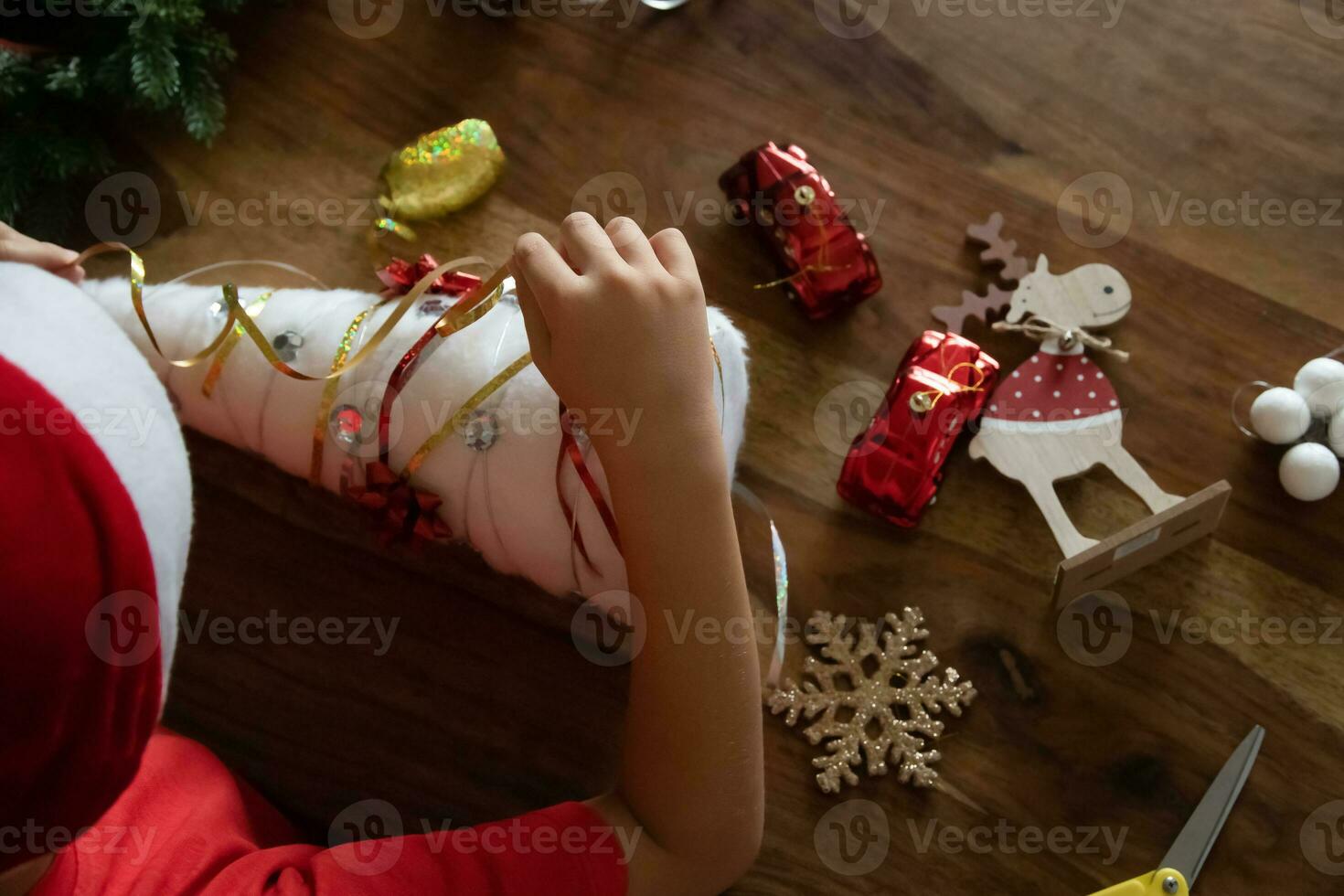 a boy in a red T-shirt and a red hat makes crafts. a child makes a decoration for a Christmas tree. photo. handmade. view from above photo