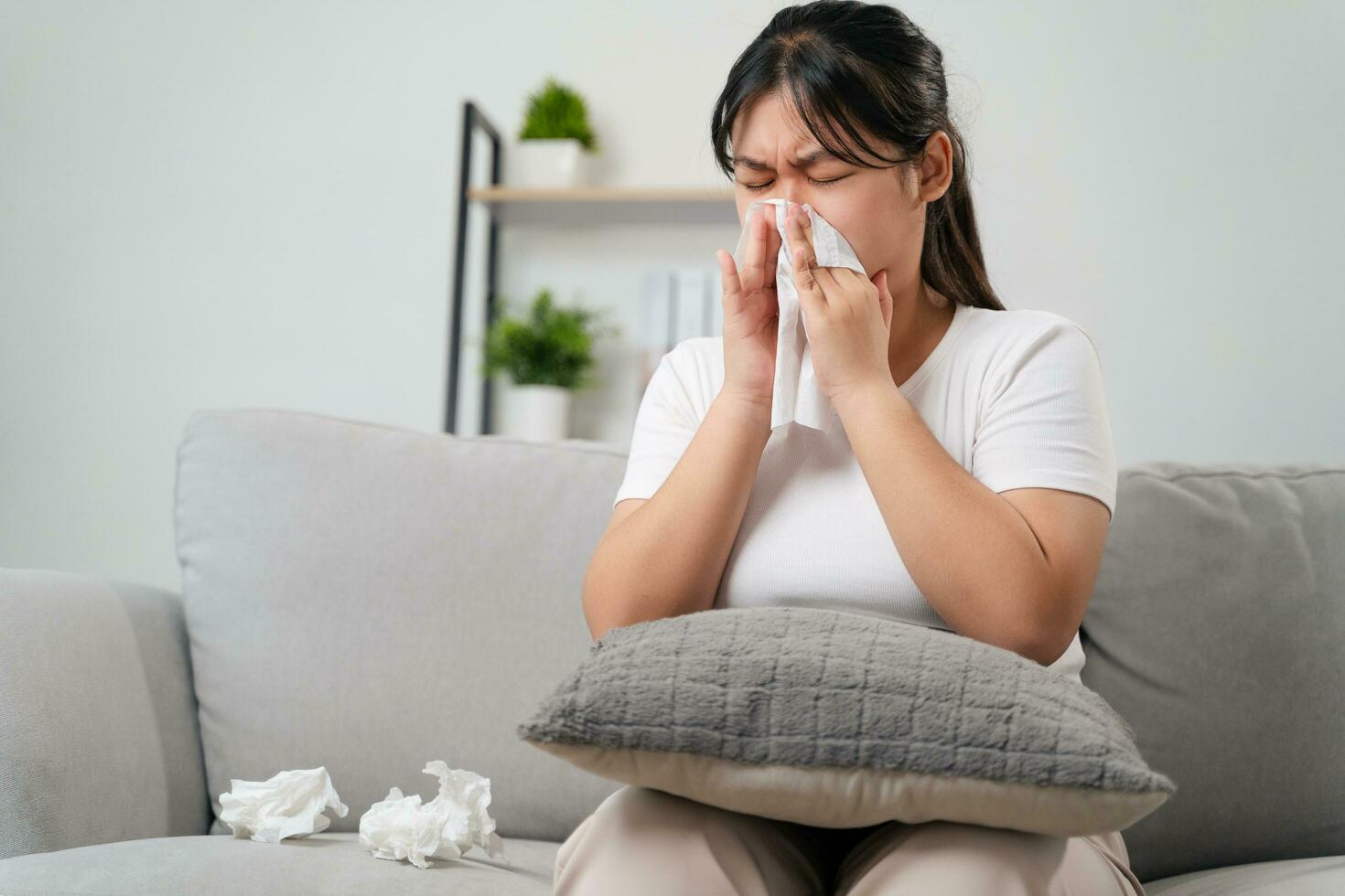 Young woman got a nose allergy sneezing sitting on the sofa at home.  Flu, Influenza, Sick, Fever, Illness. Healthcare and medical concept. photo