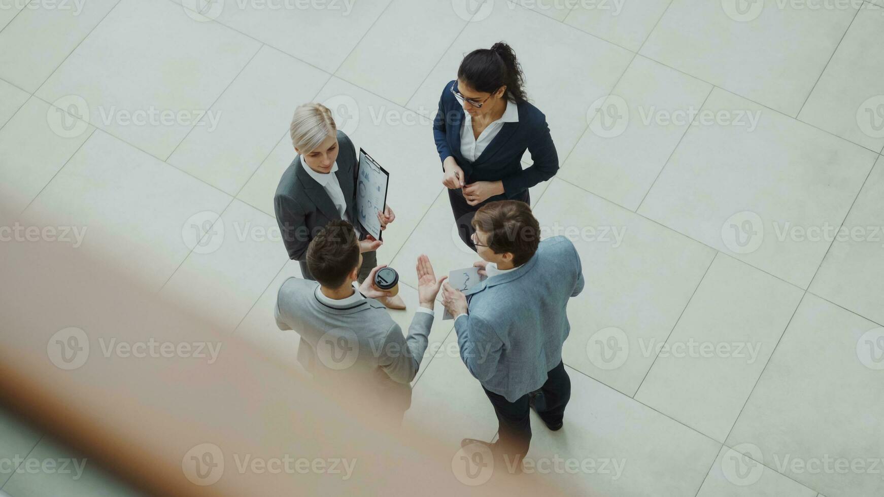 Top view of group of business people in suits discussing financial graphs in lobby of business center photo