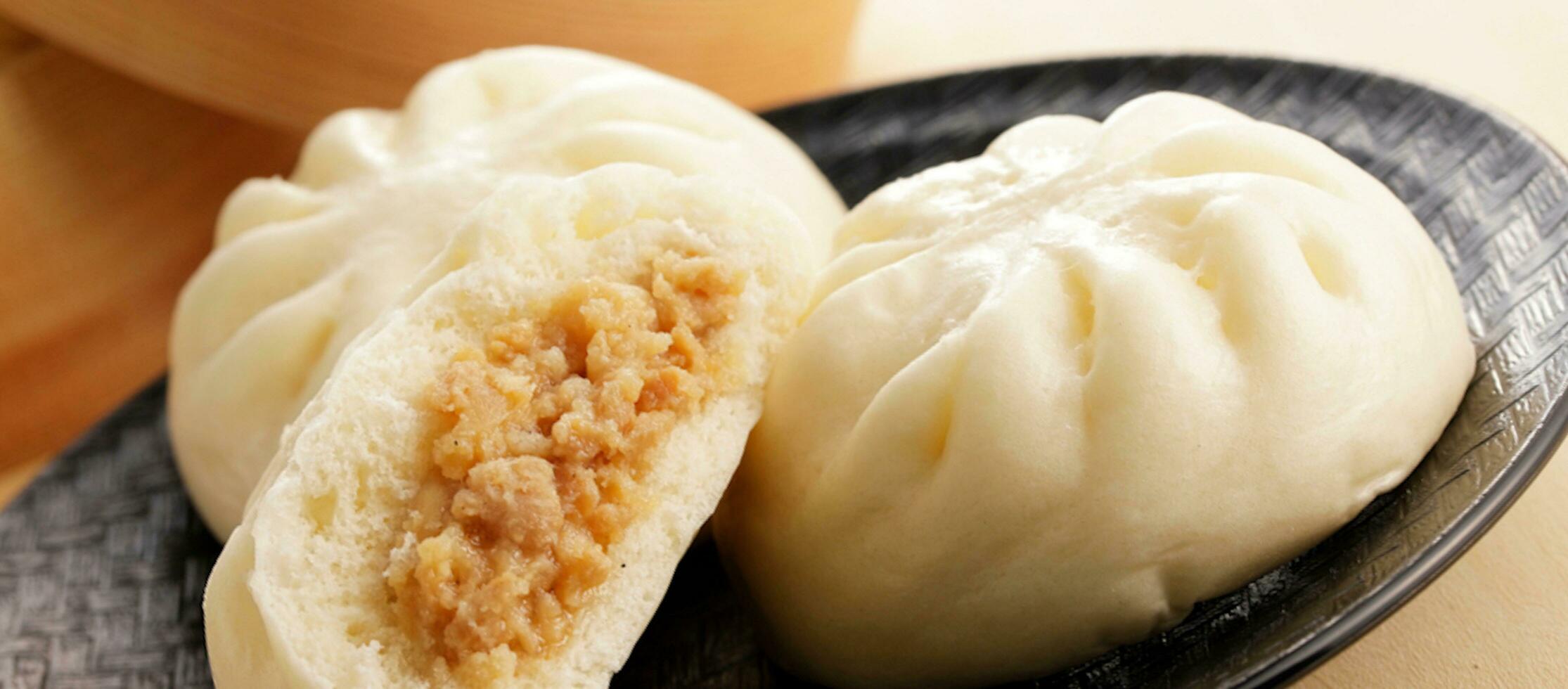 chino alimento, baozi es un tradicional delicadeza en porcelana, un pan comida fotografía entonces tentador, delicioso baozi, chino al vapor carne bollo es Listo a comer en servicio plato y buque de vapor foto