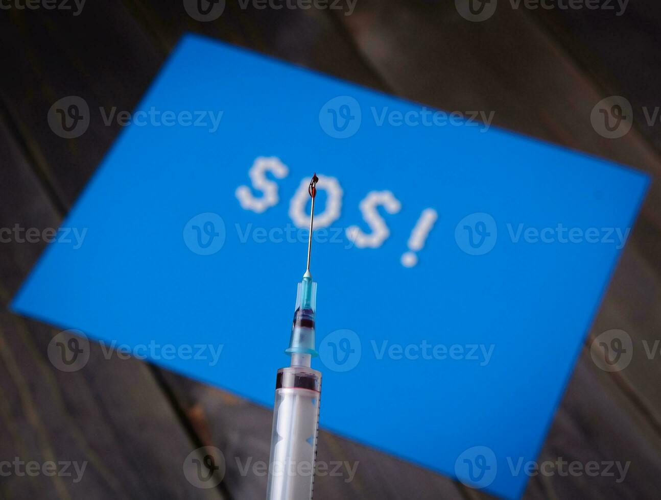 jeringuilla y llamada de socorro desde pastillas en un azul antecedentes. prevención de viral enfermedades. foto