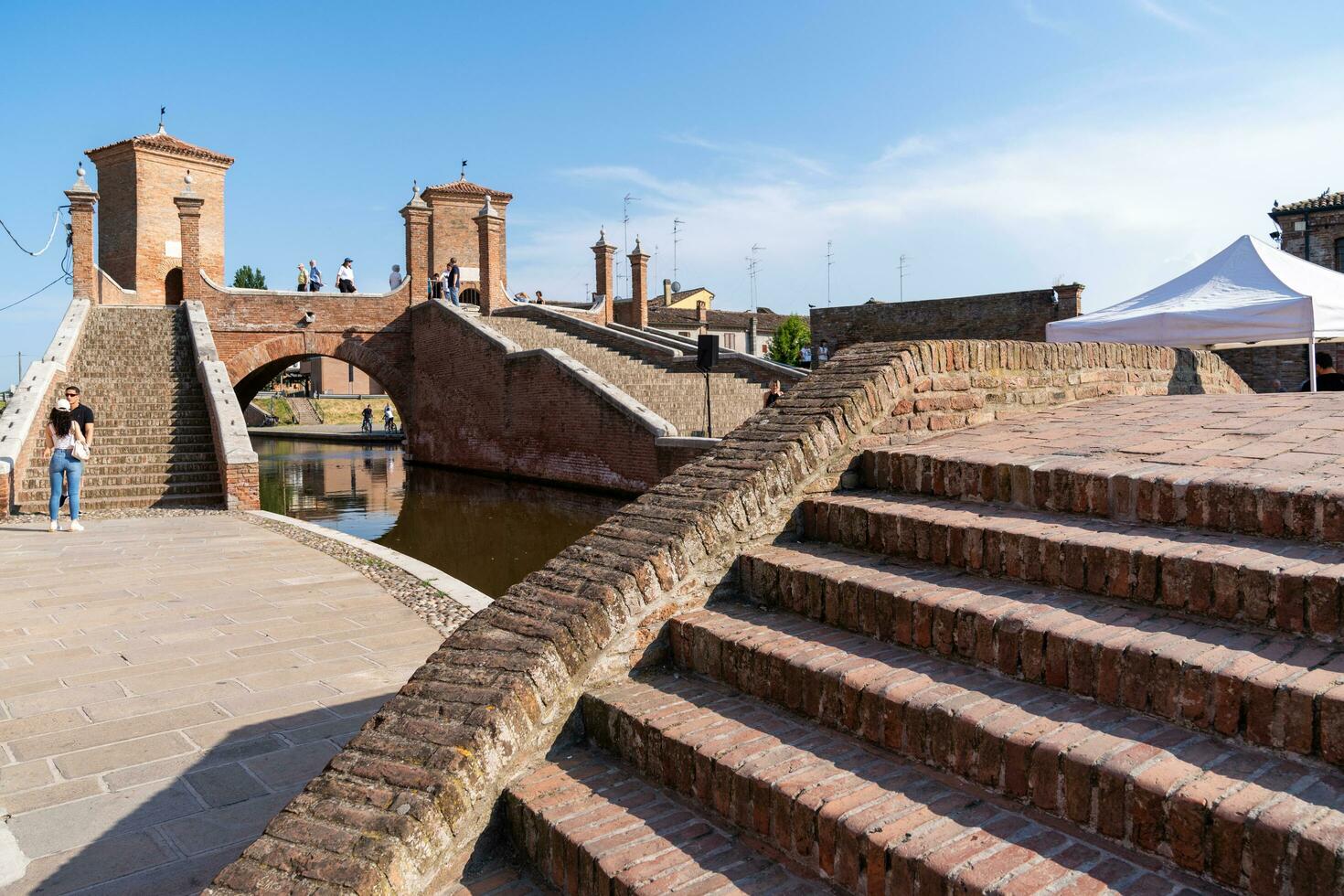 Comacchio ,Italy-June 2, 2023-people stroll in Comacchio in front off the  famous three bridges during a sunny day photo