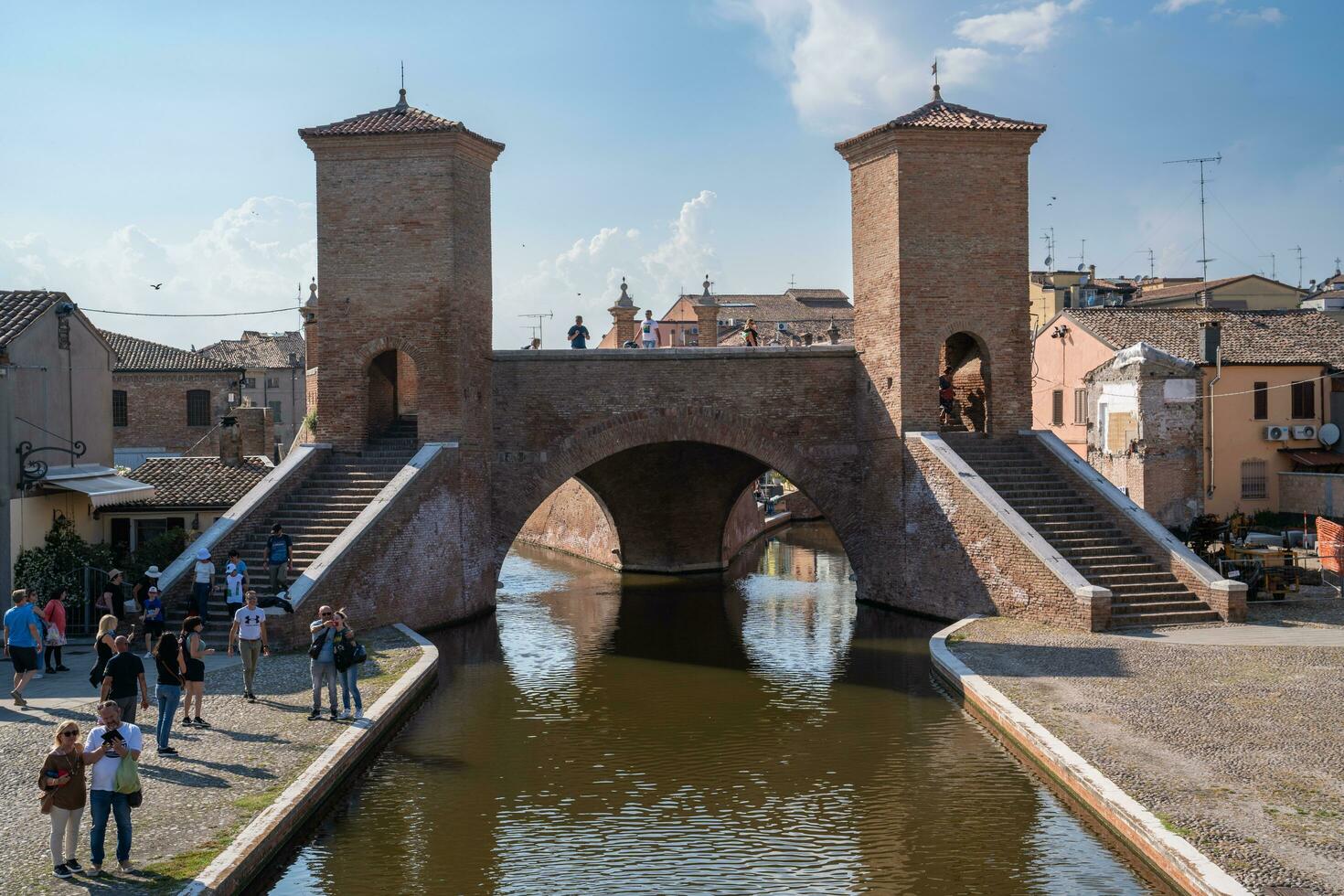 Comacchio ,Italy-June 2, 2023-people stroll in Comacchio in front off the  famous three bridges during a sunny day photo