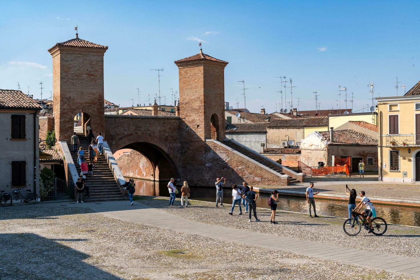 Comacchio ,Italy-June 2, 2023-people stroll in Comacchio in front off the  famous three bridges during a sunny day photo