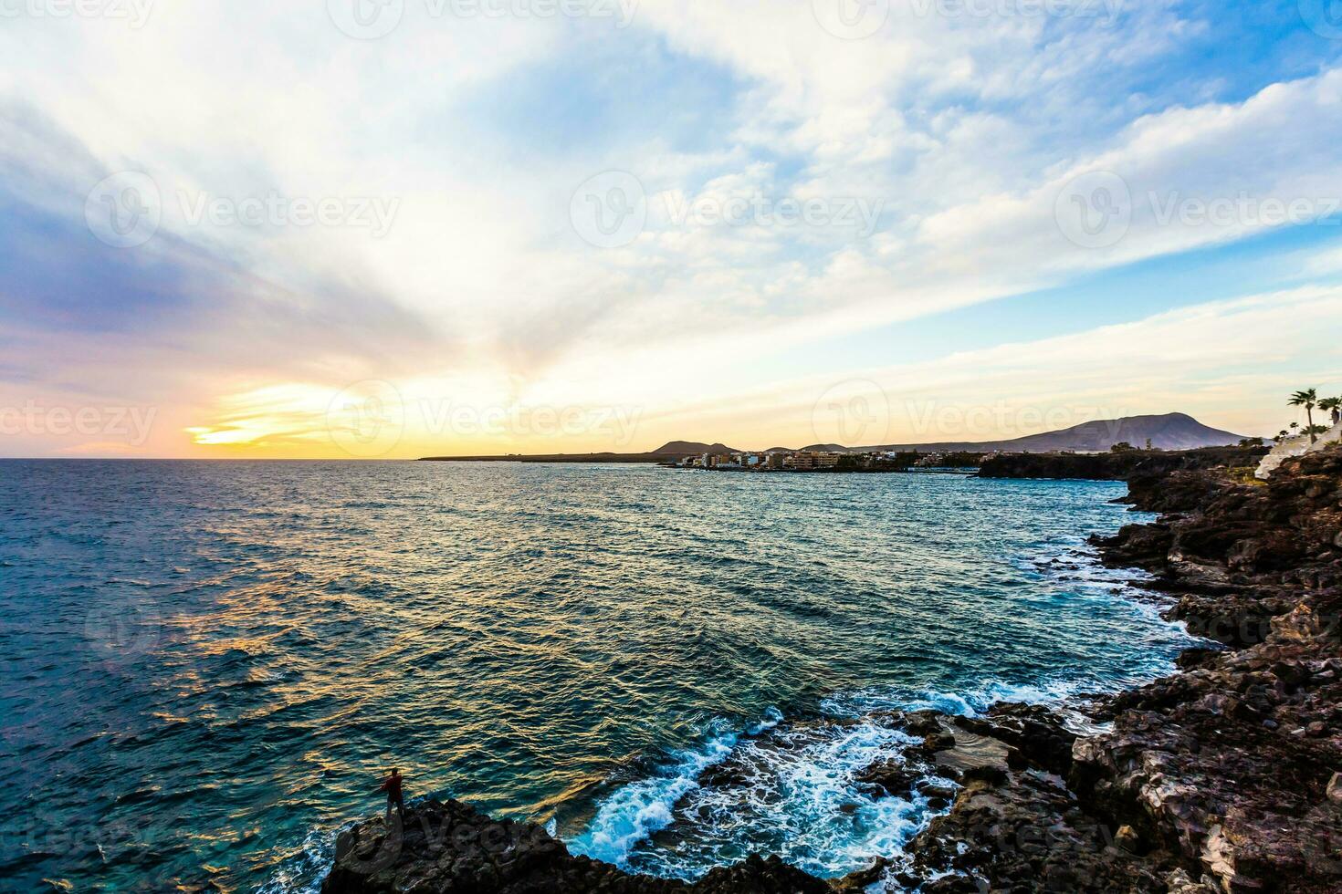 marina con atlántico Oceano y el cielo a crepúsculo, piedras en el playa y pescadores en el muelle. largo exposición con borroso mar agua foto